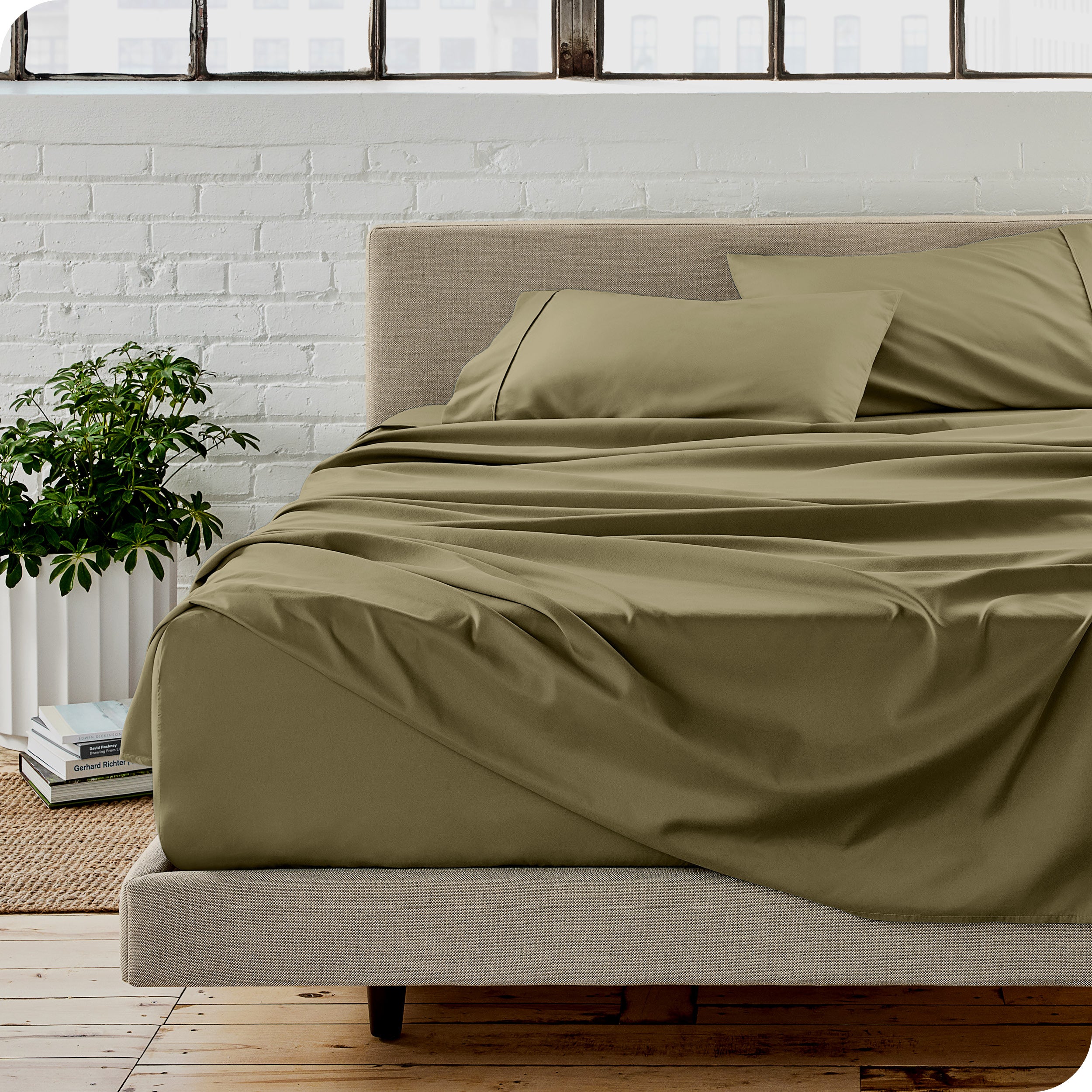Microfiber sheets on a bed with a brick wall behind it