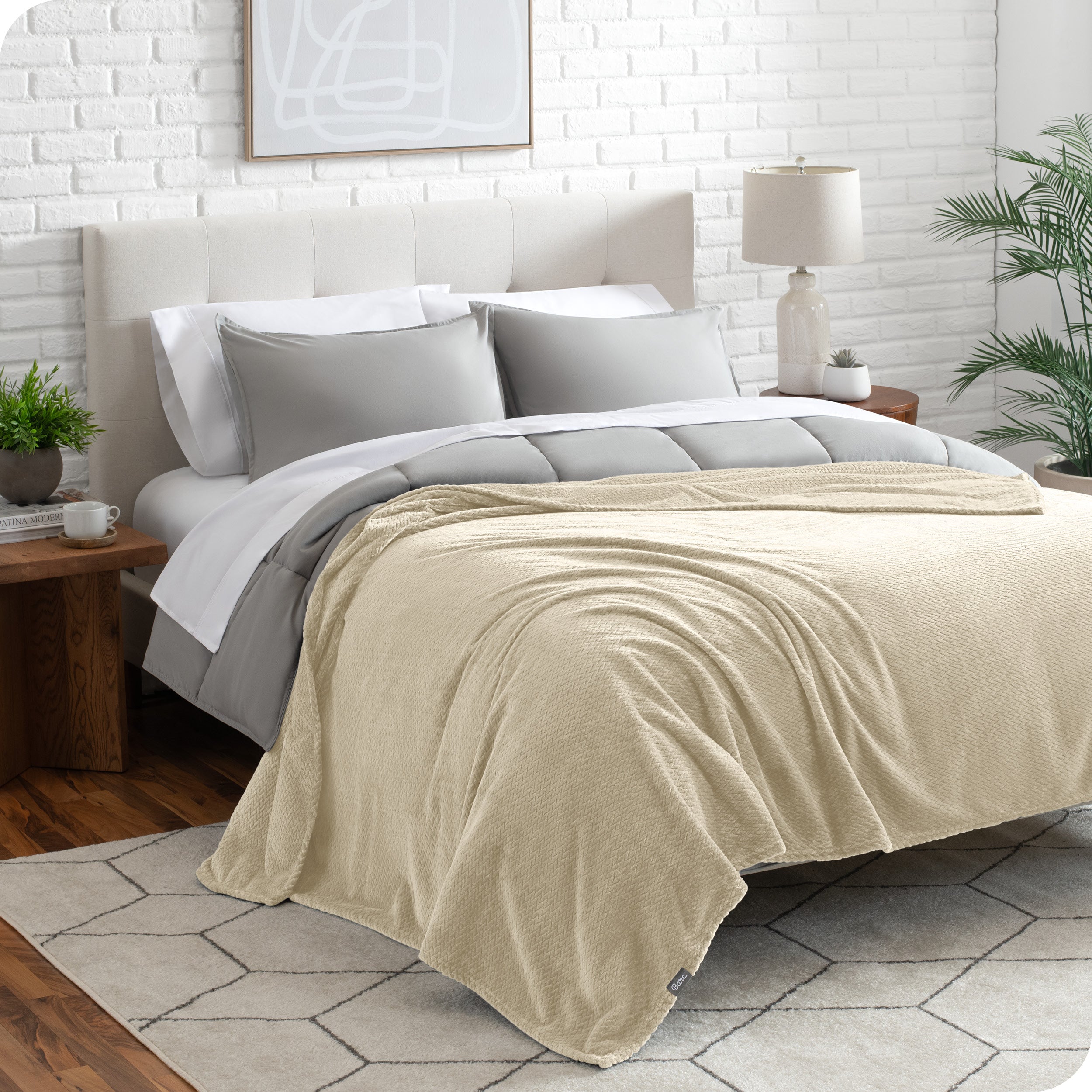 A textured microplush blanket is draped over a bed made with grey duvet set