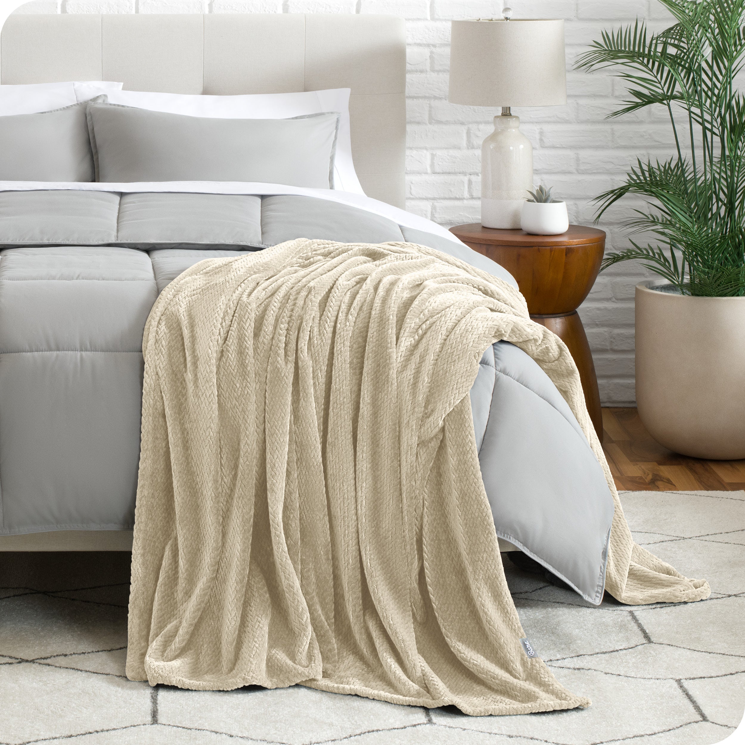 A textured microplush blanket is hanging over the corner of a bed