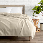 A polar fleece blanket on a bed next to a table and a large plant