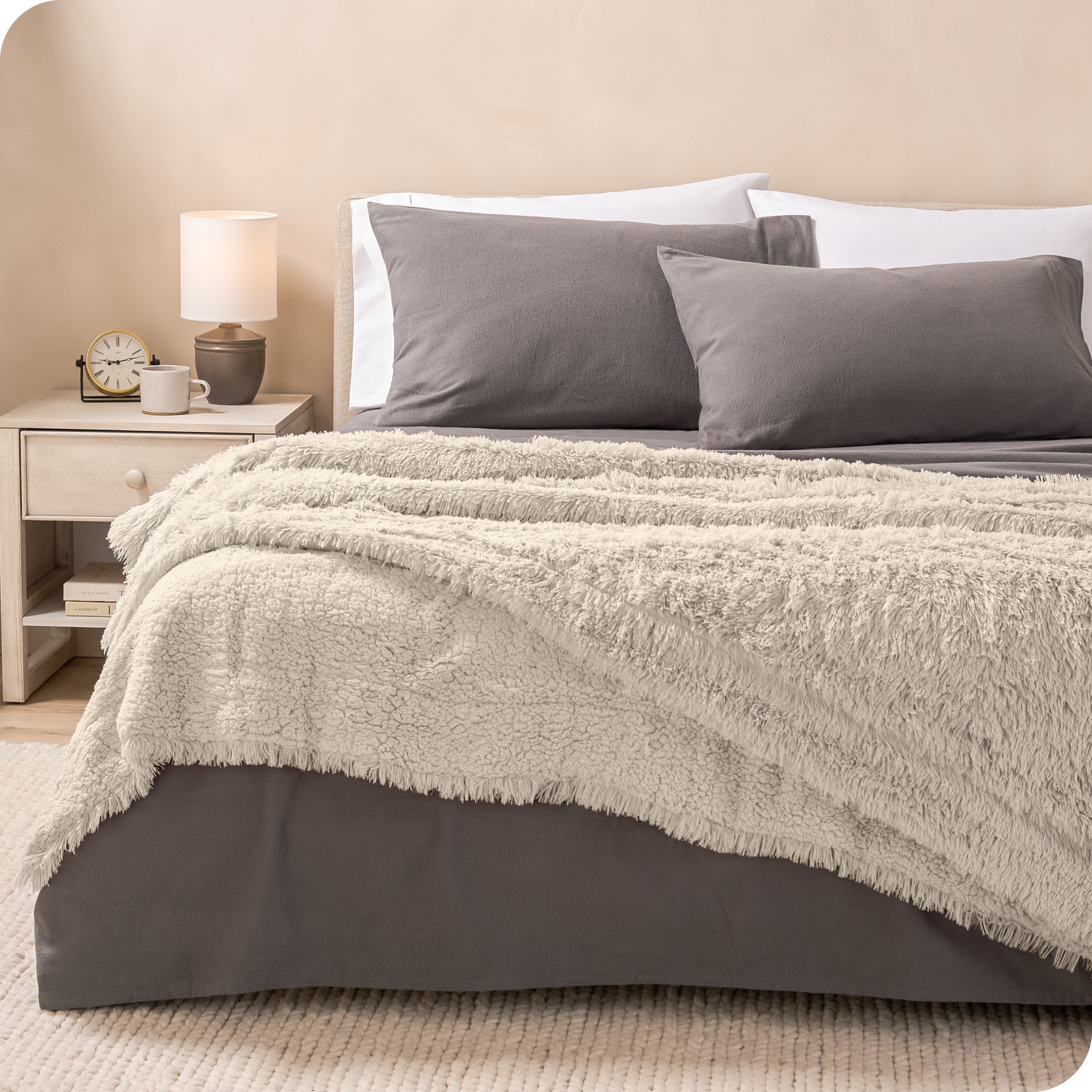 A shaggy faux fur blanket on the end of a bed
