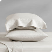 Two pillowcases on pillows stacked on a bed with matching sheets