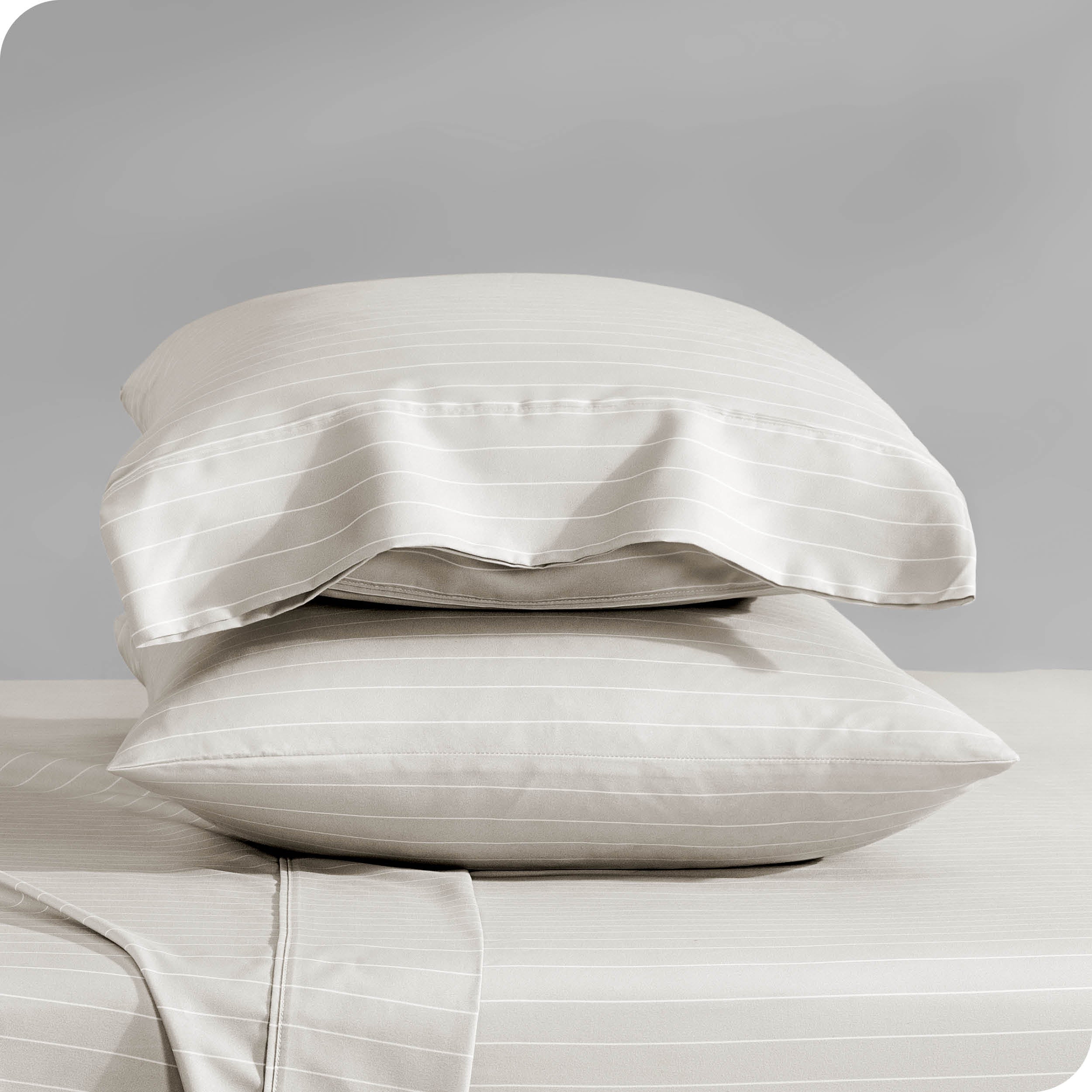 Two pillowcases on pillows stacked on a bed with matching sheets