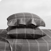Two pillowcases on pillows stacked on a bed with matching sheets