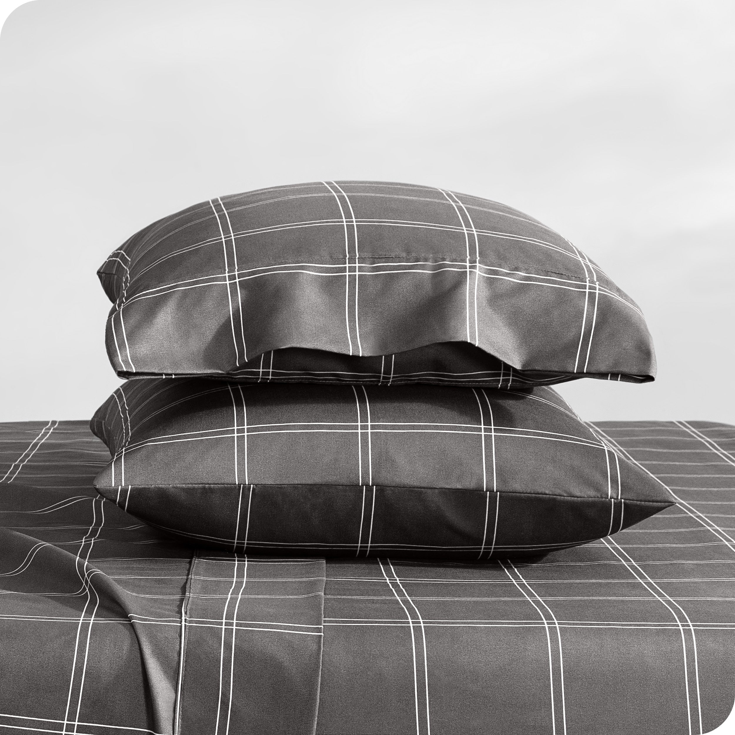 Two pillowcases on pillows stacked on a bed with matching sheets