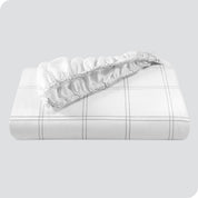 A neatly folded printed microfiber fitted sheet with elastic draped. 