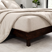 The corner of a mattress with a fitted sheet and comforter on it