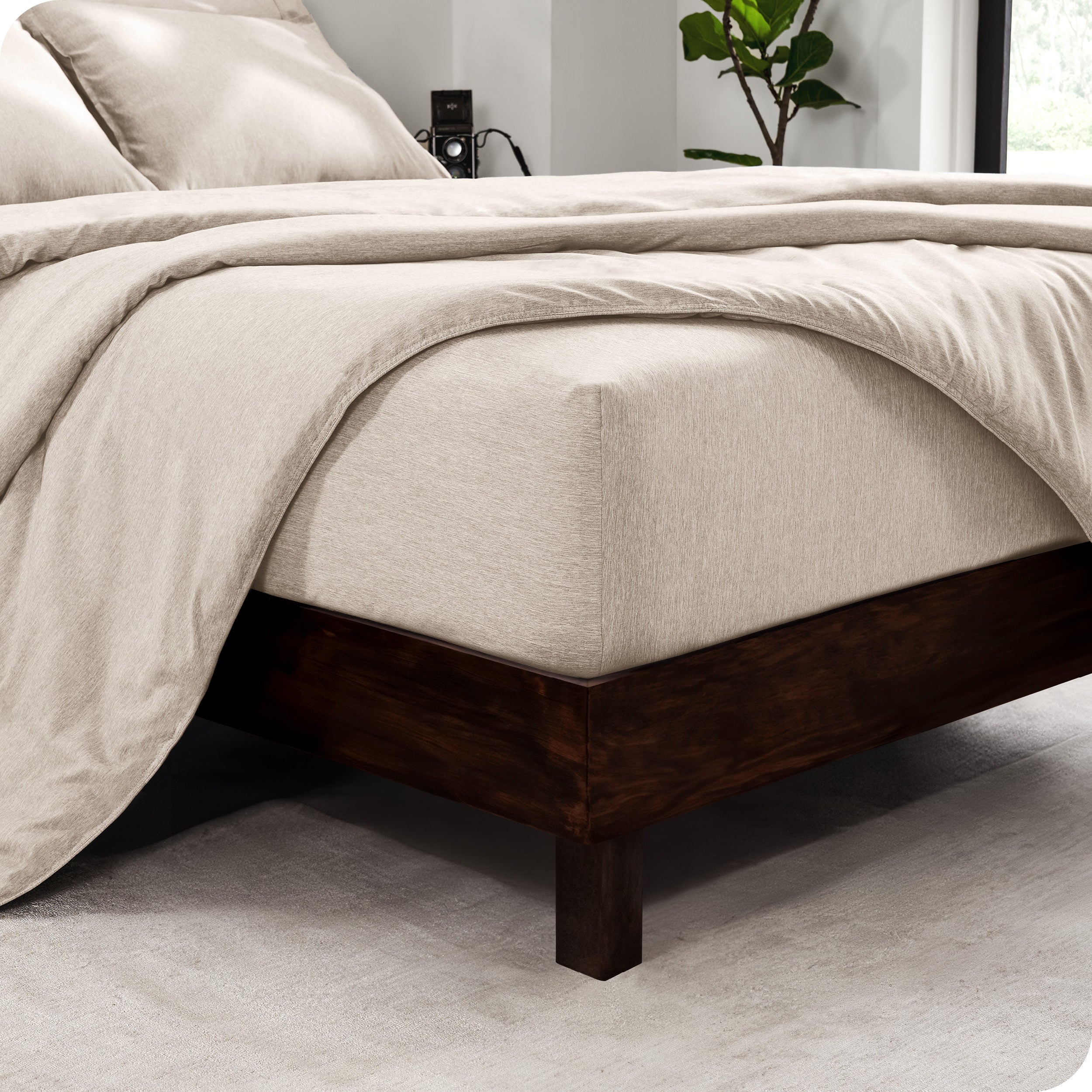 The corner of a mattress with a fitted sheet and comforter on it