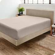 Corner view of a modern bed with a microfiber fitted sheet on the mattress. 