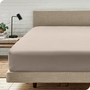 A bed with a microfiber fitted sheet on the mattress. 