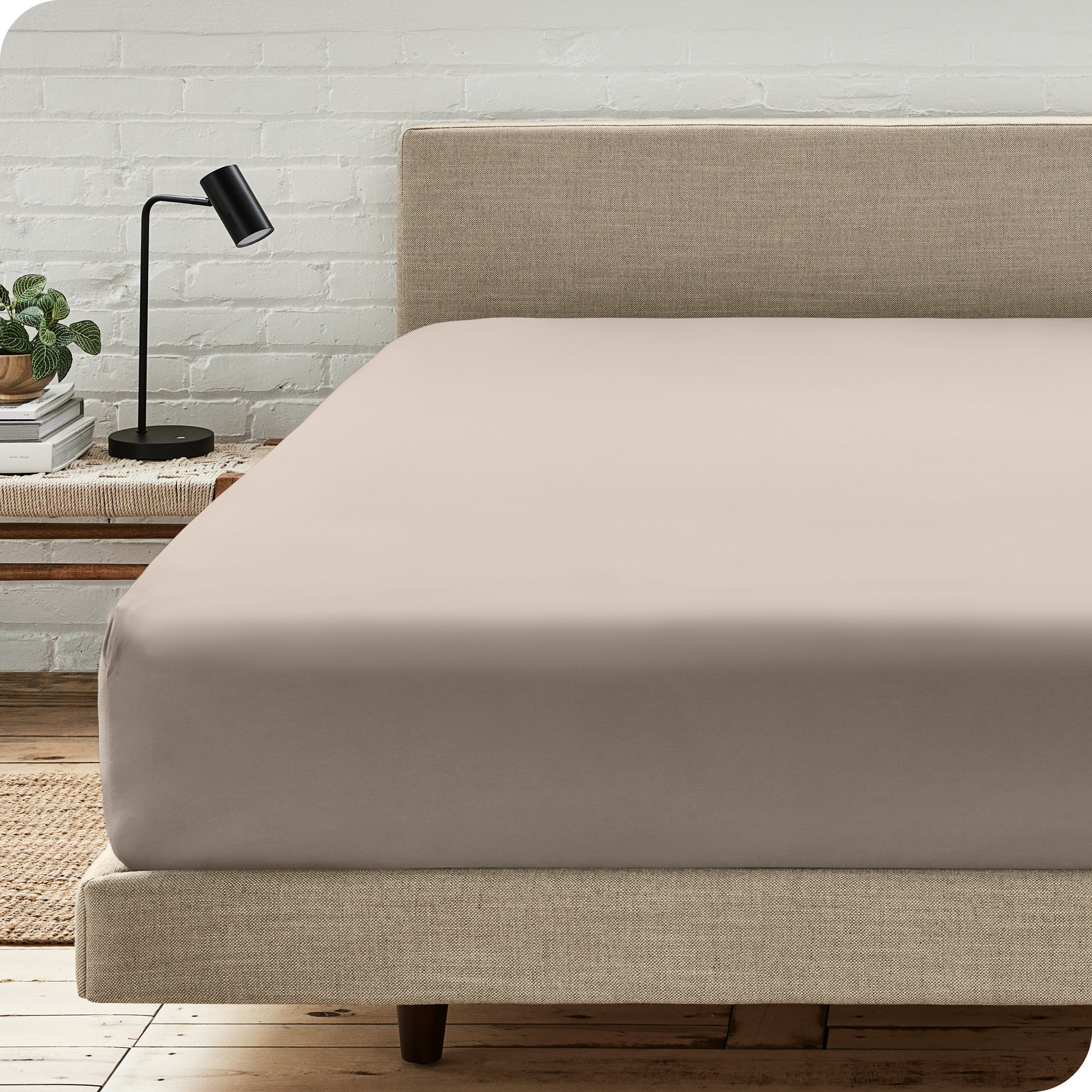 A bed with a microfiber fitted sheet on the mattress. 