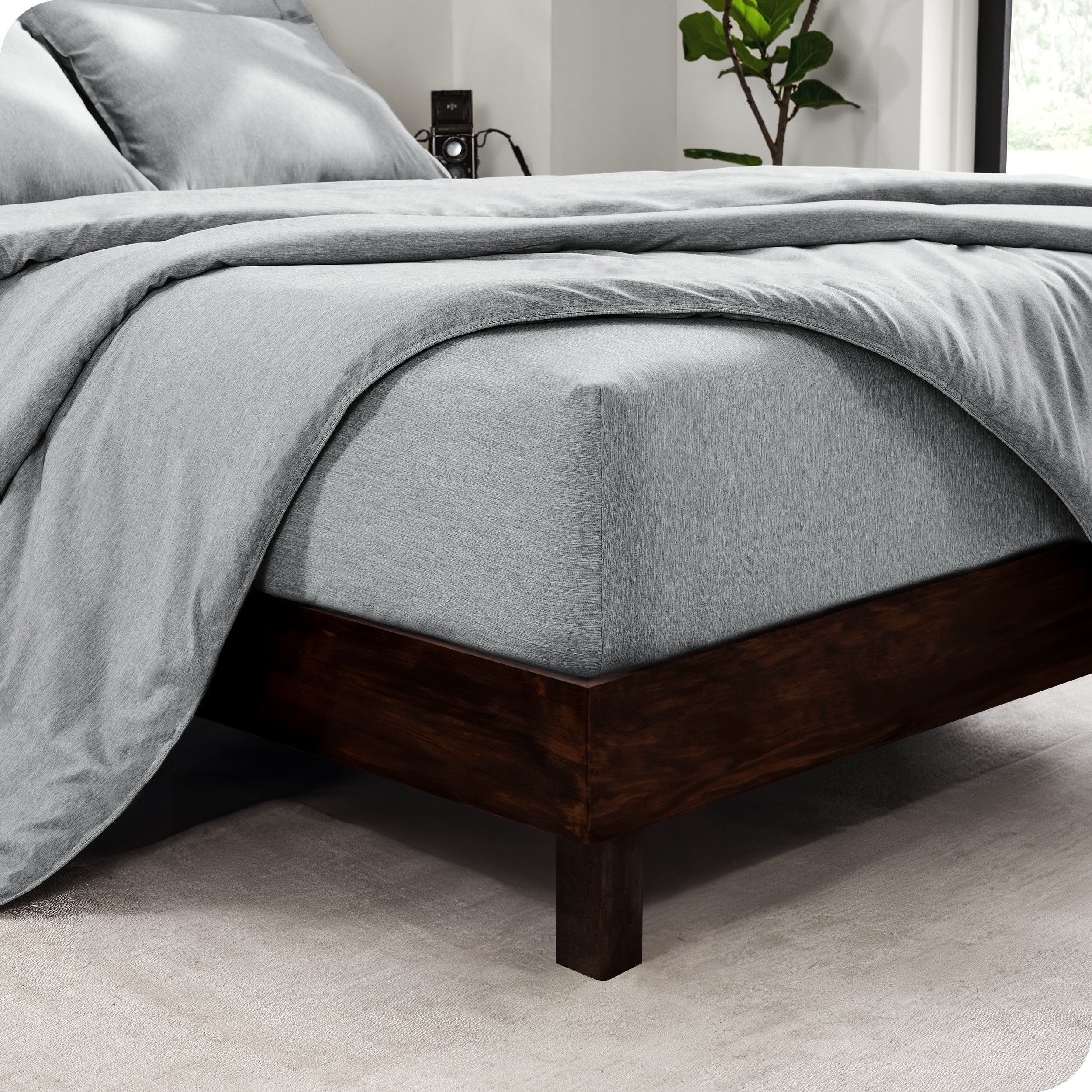 The corner of a mattress with a fitted sheet and comforter on it