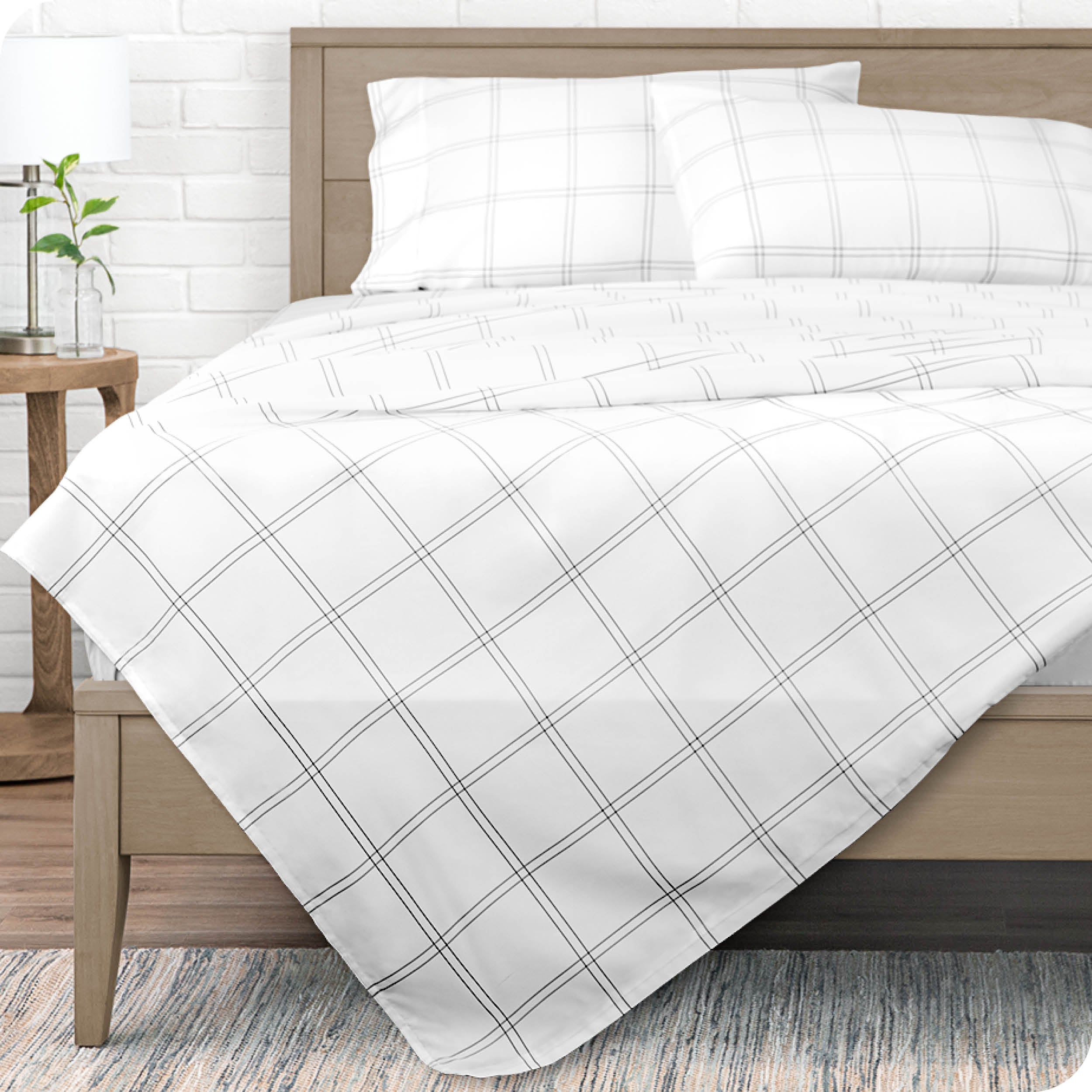 View from end of a modern bed with microfiber flat sheet draped over. 