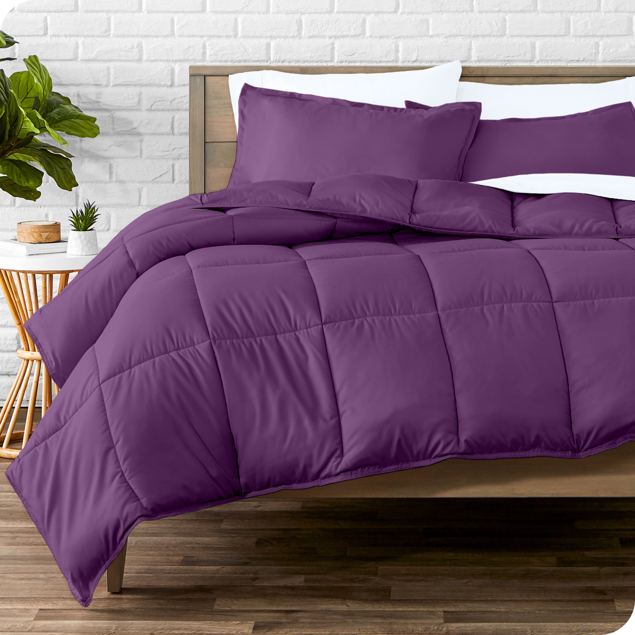 A wooden bed frame with sheets, pillow shams and a comforter on the bed