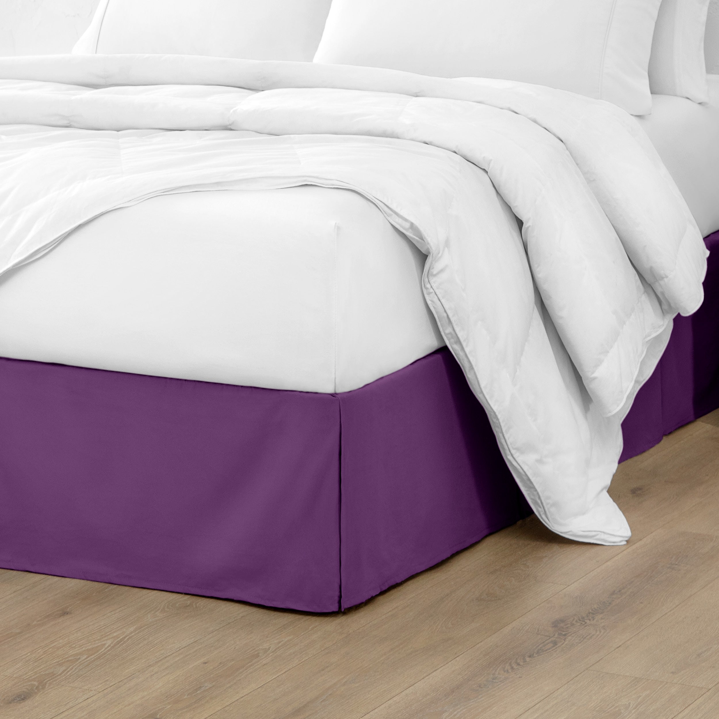 The corner of a bed with a bed skirt and comforter on it