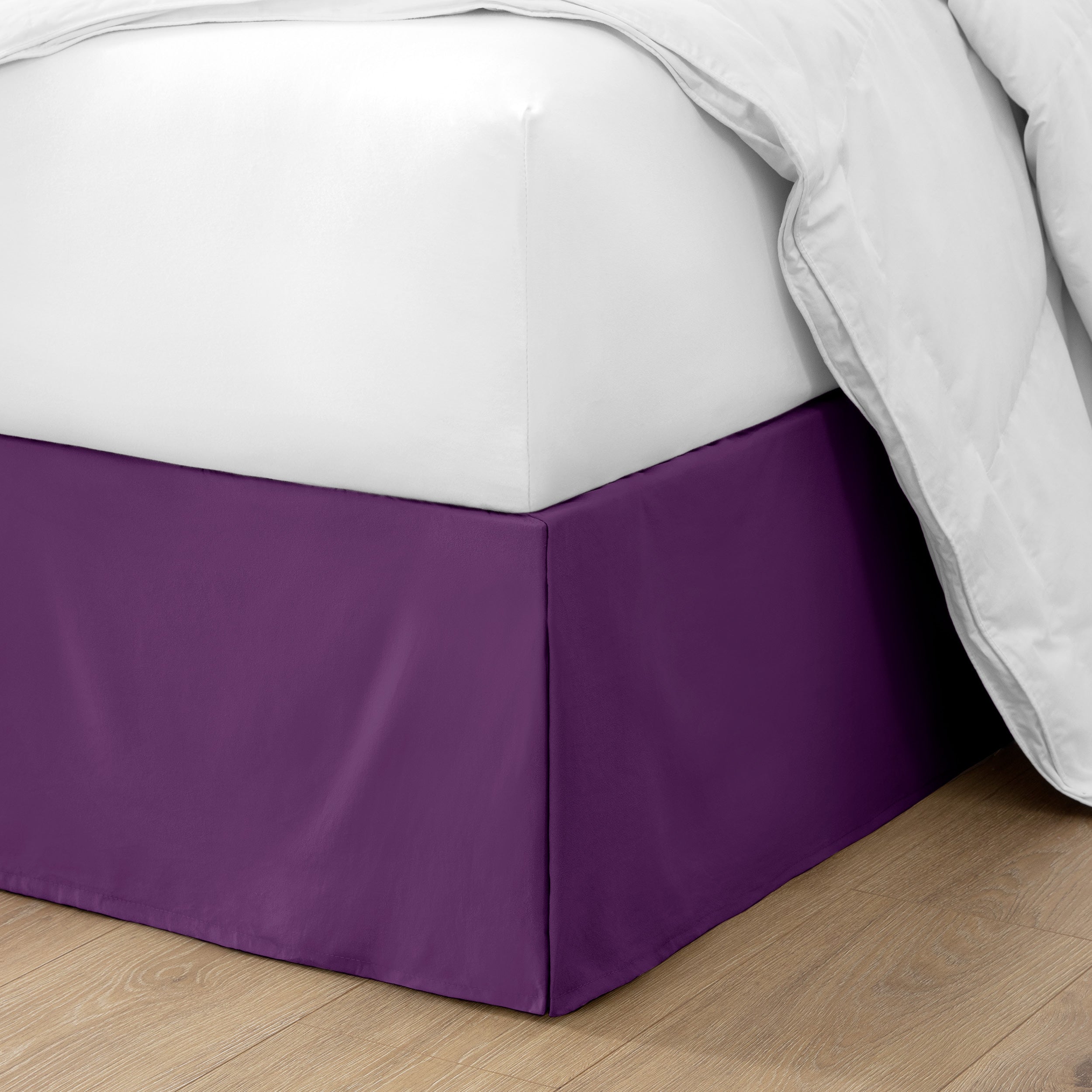The corner of a bed with a bed skirt and comforter on it