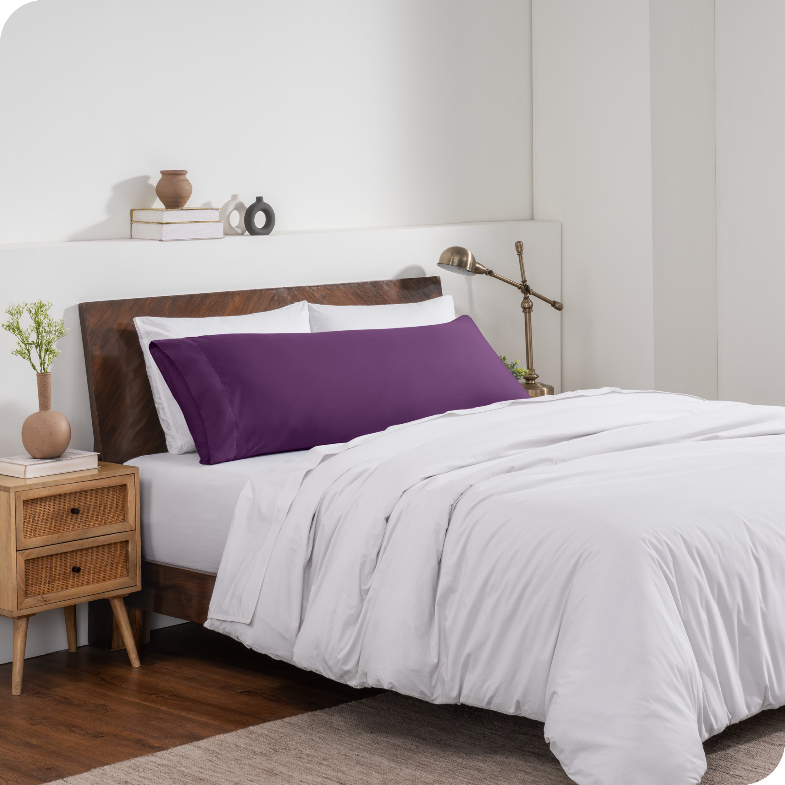 A body pillow cover on a pillow on a bed made with all white bedding