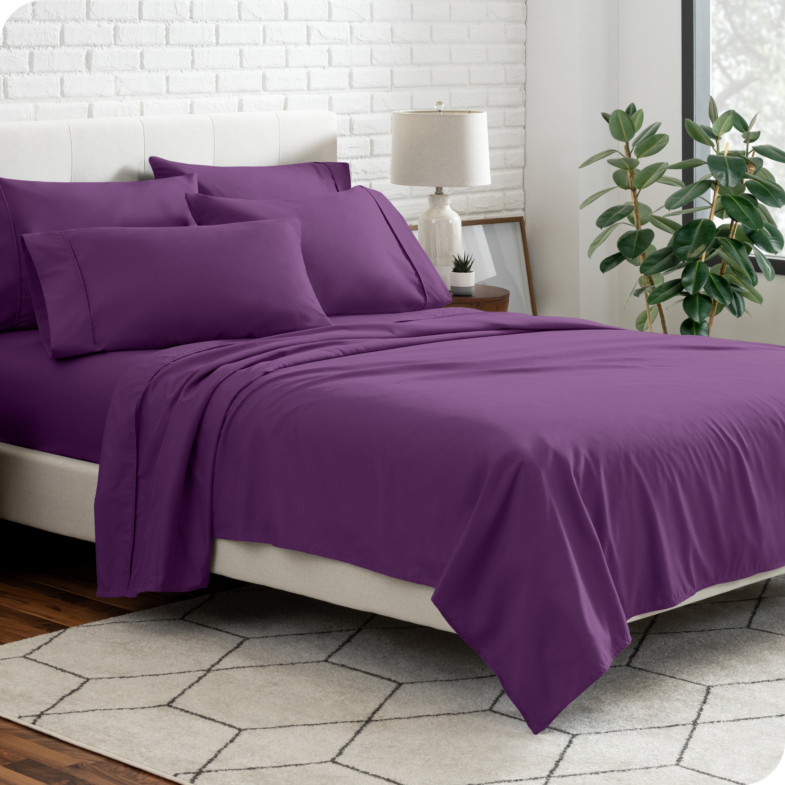 A bedroom setting with a bed made with the microfiber bed sheets and four pillows.