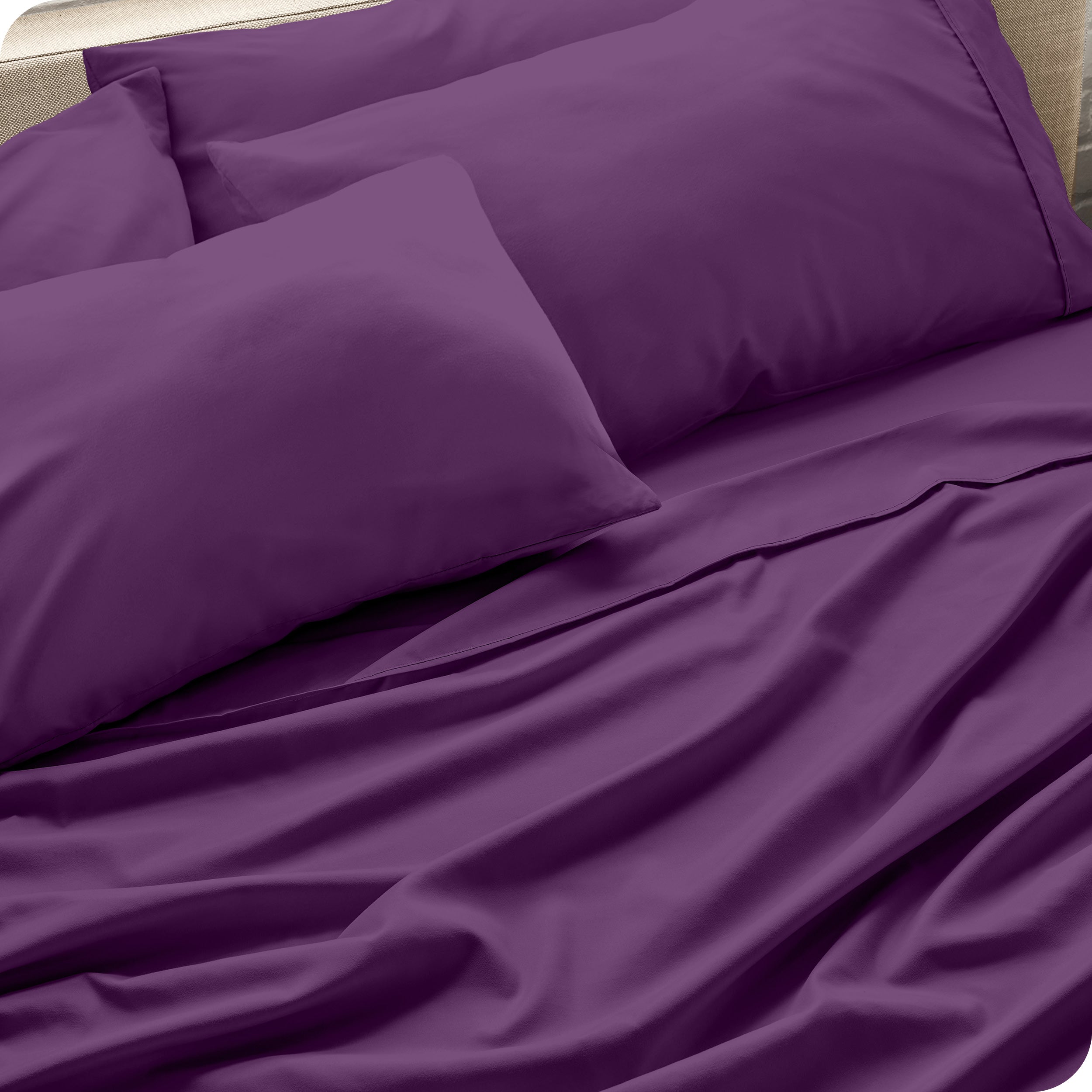 Close up of the microfiber bed sheets on a bed with four pillows.