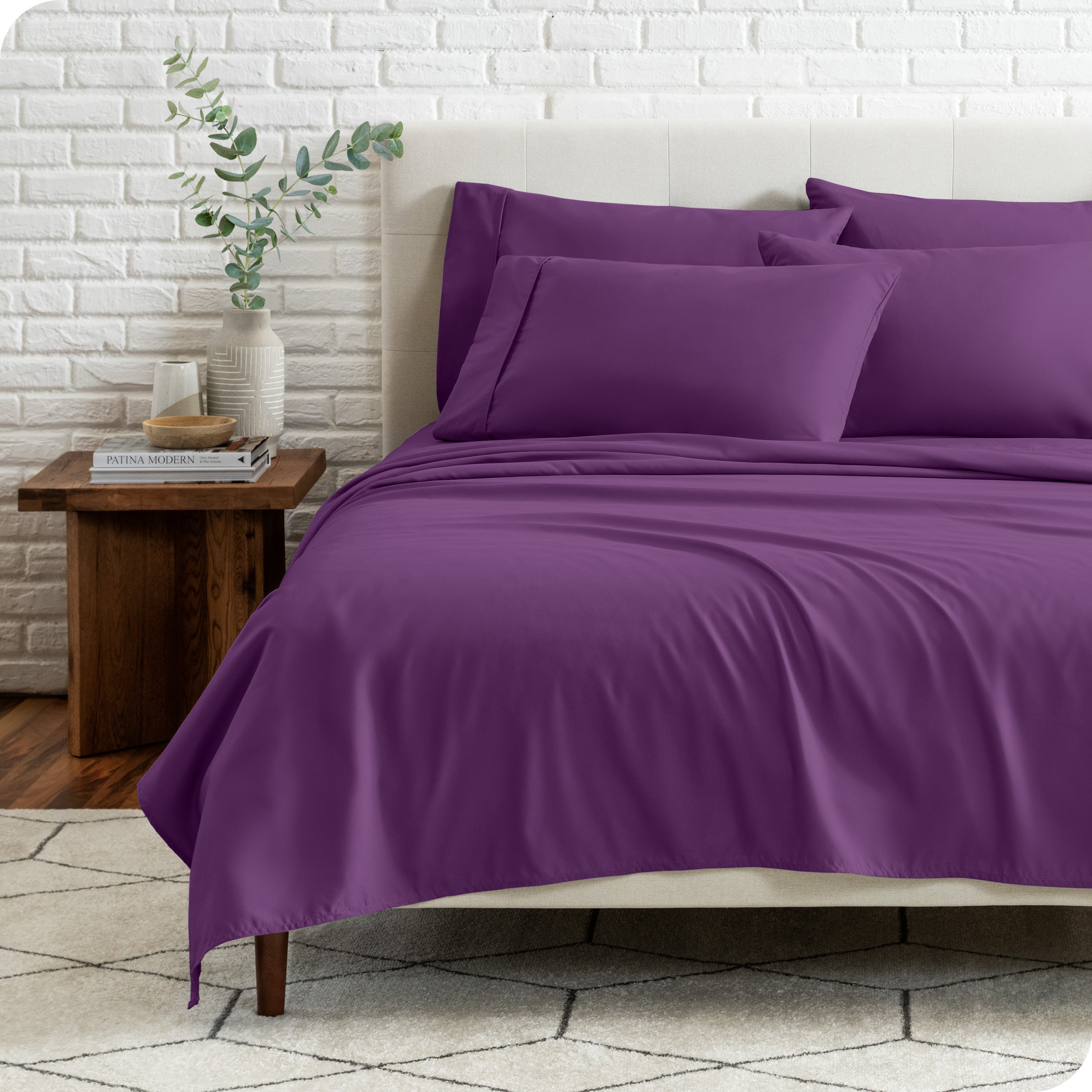 End view of a modern bed with the microfiber sheets on the bed with four pillows.