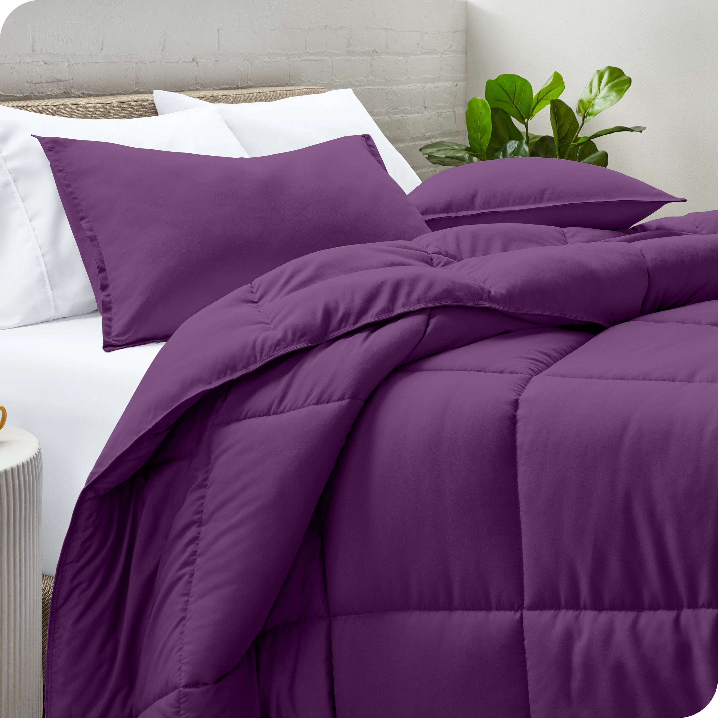 A side view of a modern bed with a comforter set and pillows on the bed