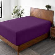 A wide corner view of a modern bed made with a microfiber fitted sheet on the mattress. 