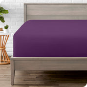 A modern bed with a fitted microfiber sheet on it