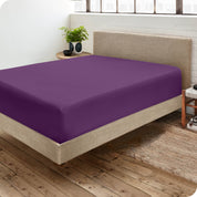 Corner view of a modern bed with a microfiber fitted sheet on the mattress. 