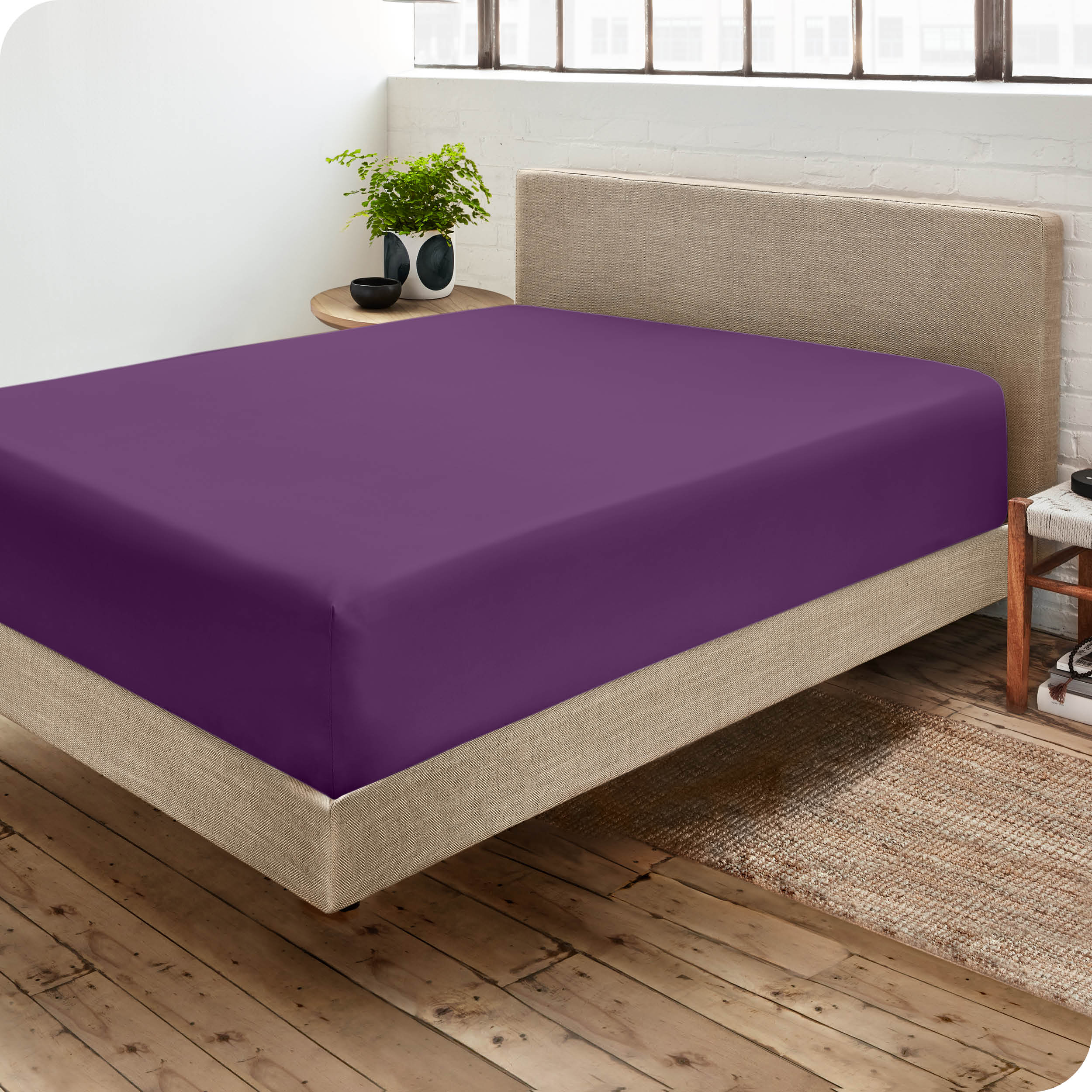 Corner view of a modern bed with a microfiber fitted sheet on the mattress. 