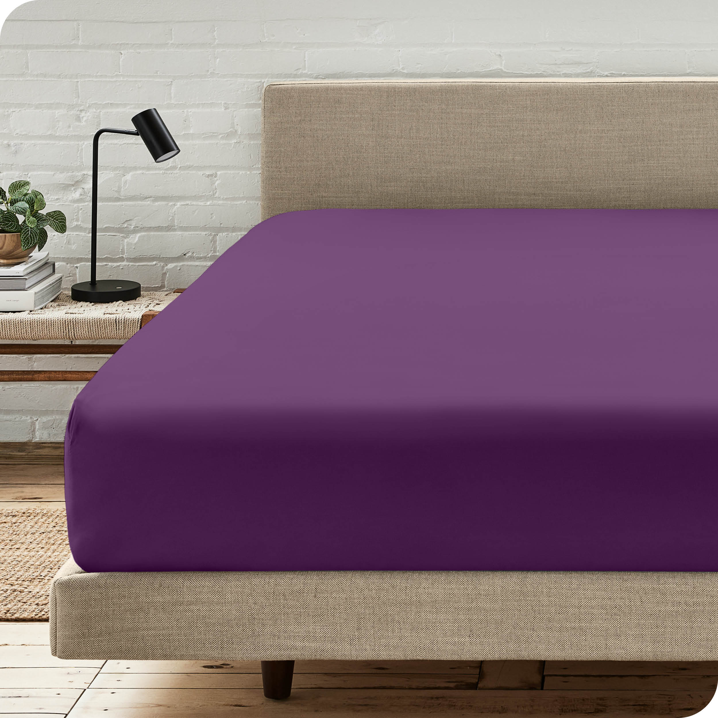 A bed with a microfiber fitted sheet on the mattress. 