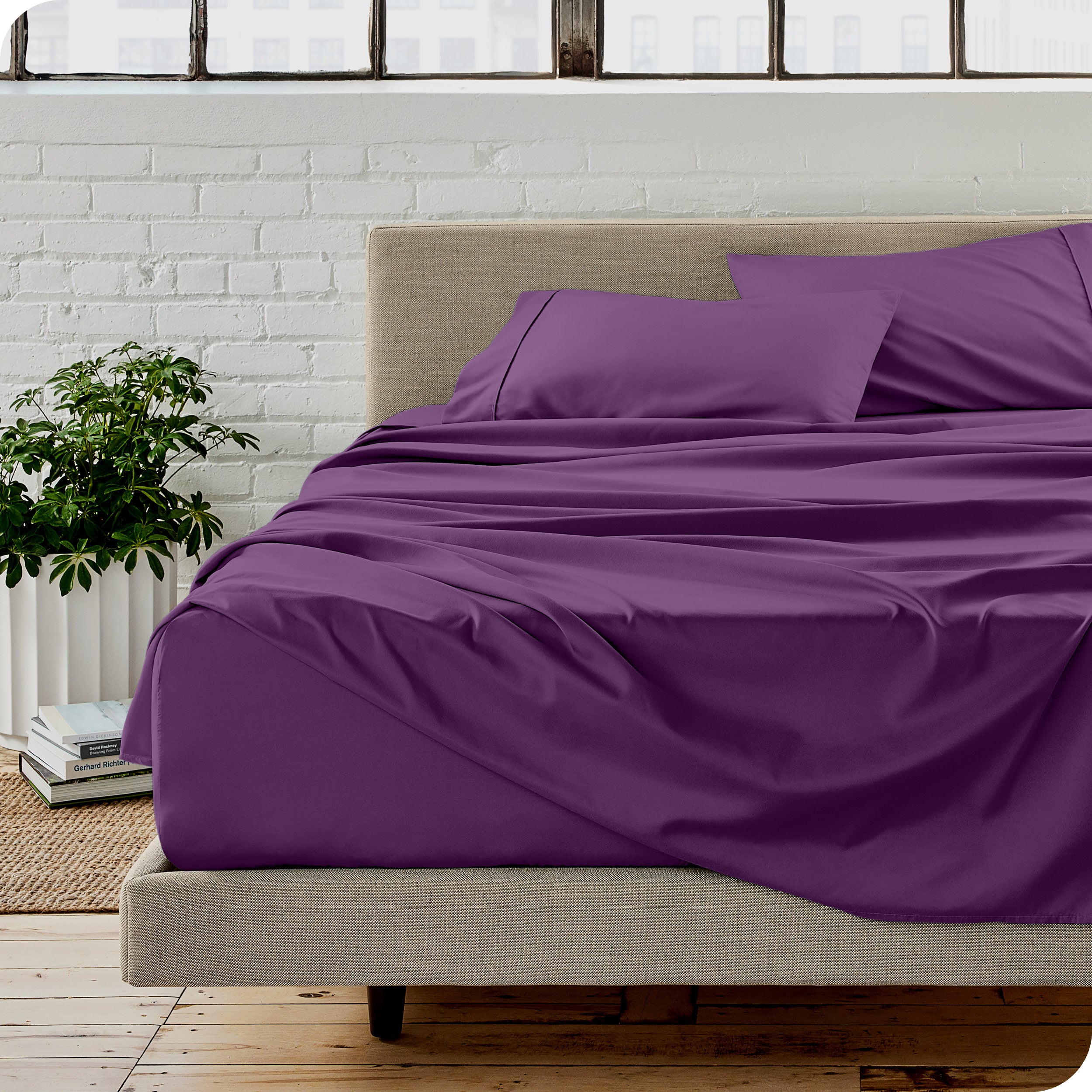 Microfiber sheets on a bed with a brick wall behind it