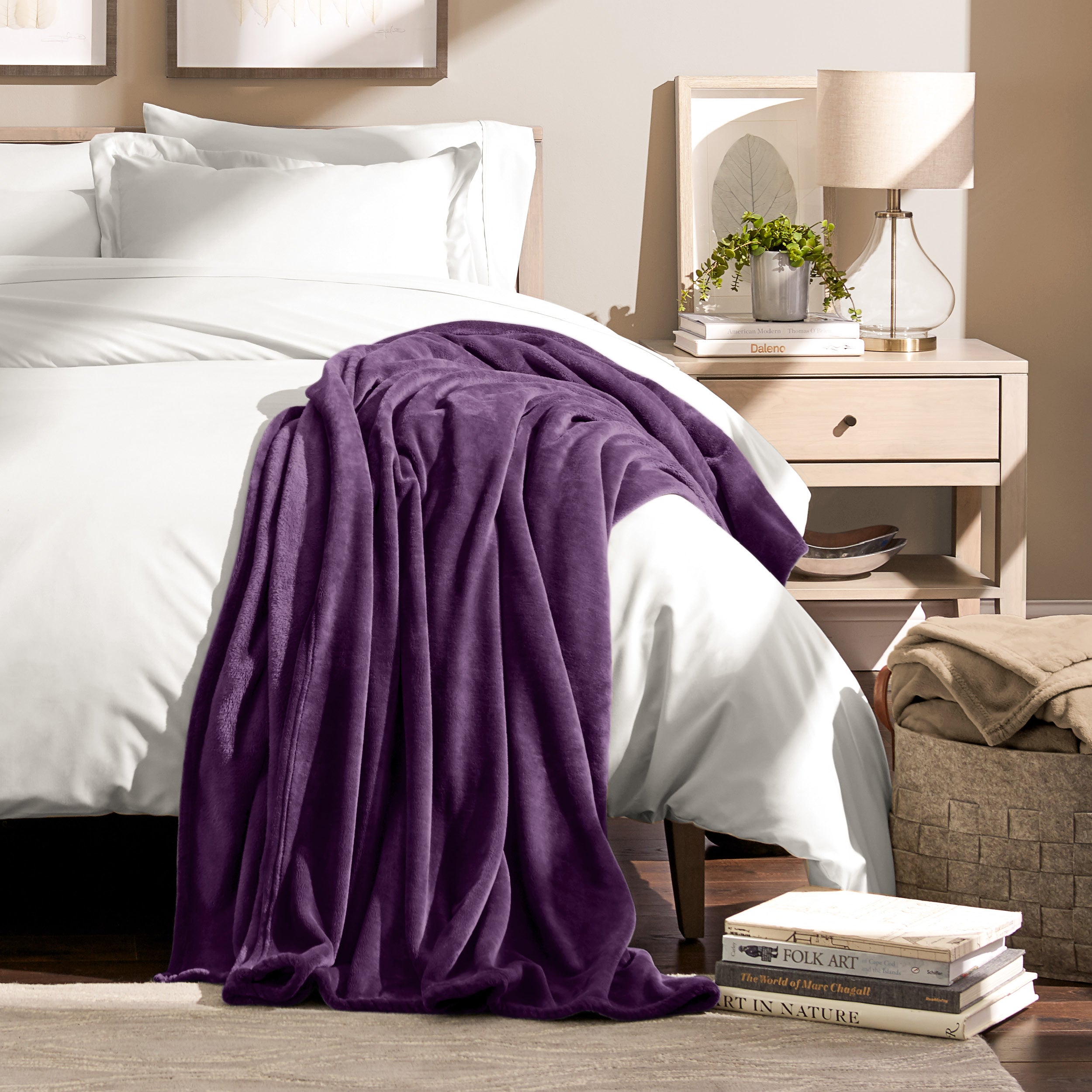 A woman sitting on a bed wrapped in a microplush blanket