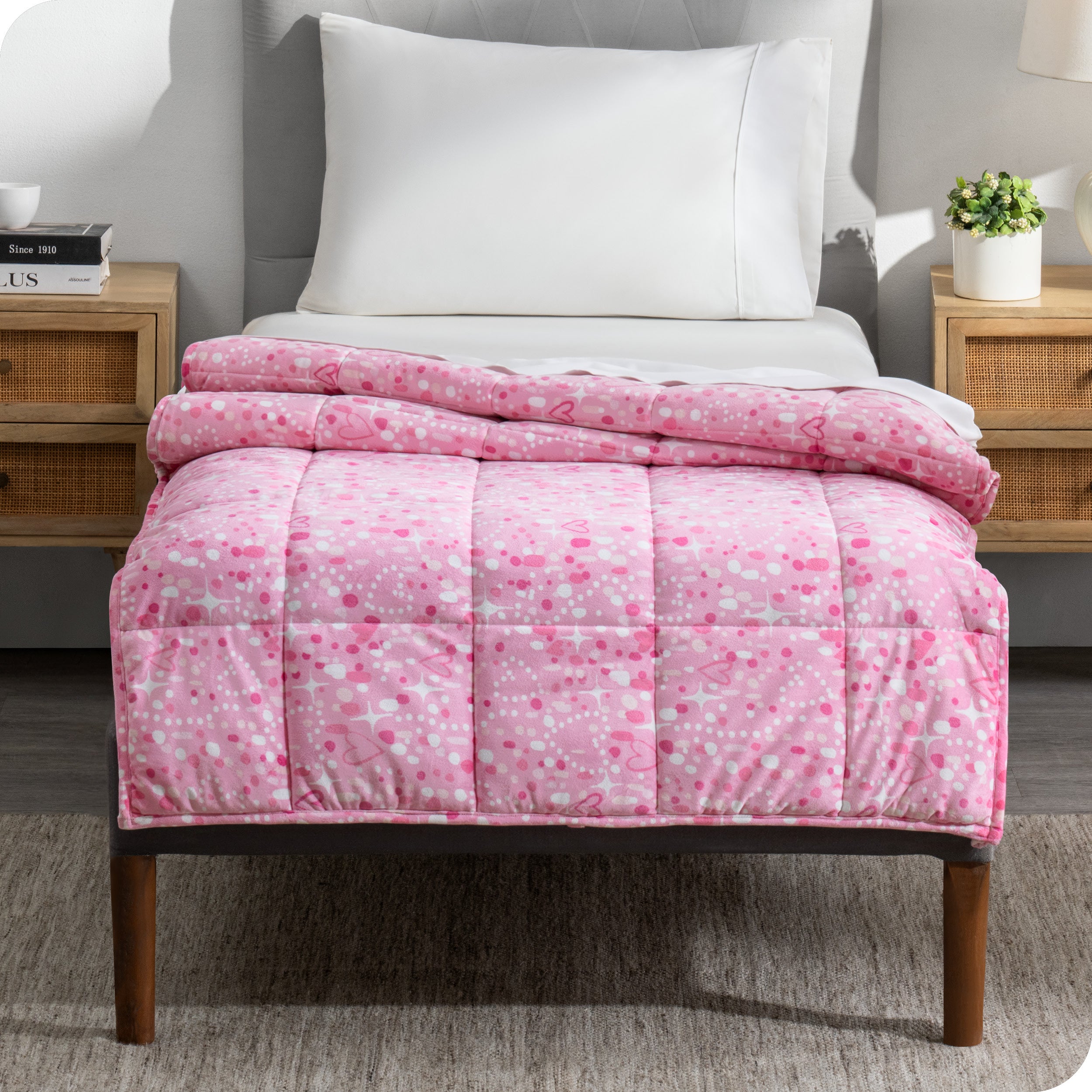 A printed weighted blanket hanging off the end of a twin size bed