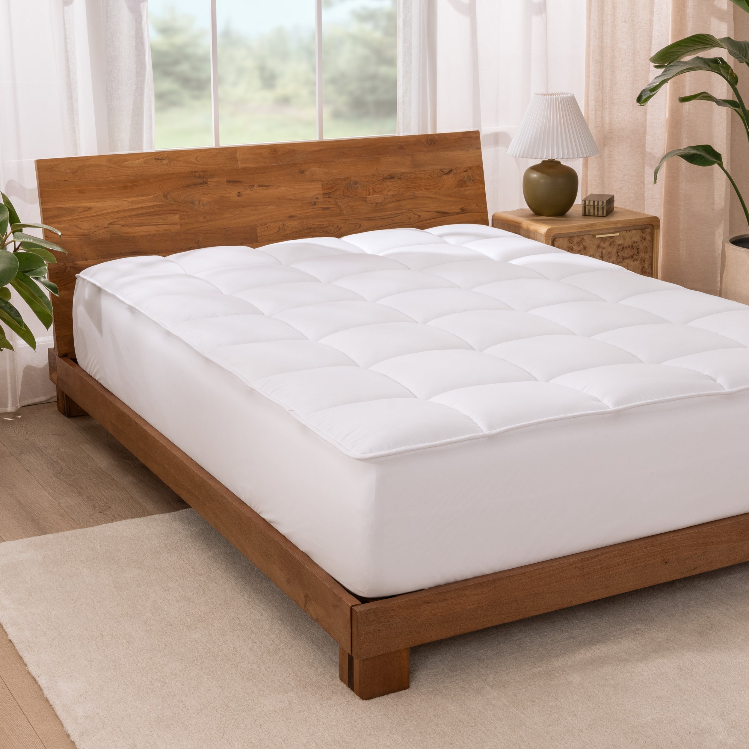 A reversible mattress pad on a bed with a wooden headboard in a right room.