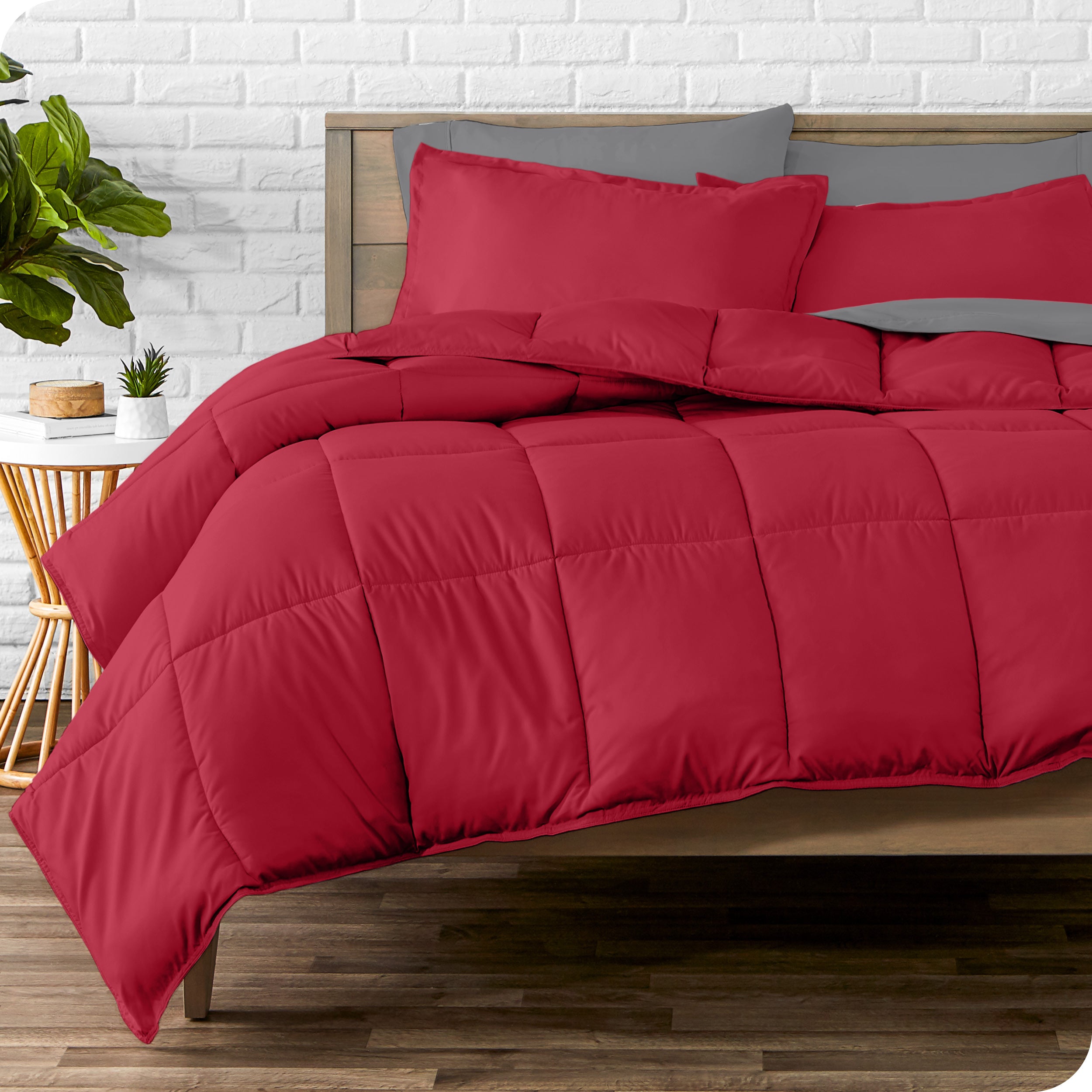 A wooden bed frame with sheets, pillow shams and a comforter on the bed
