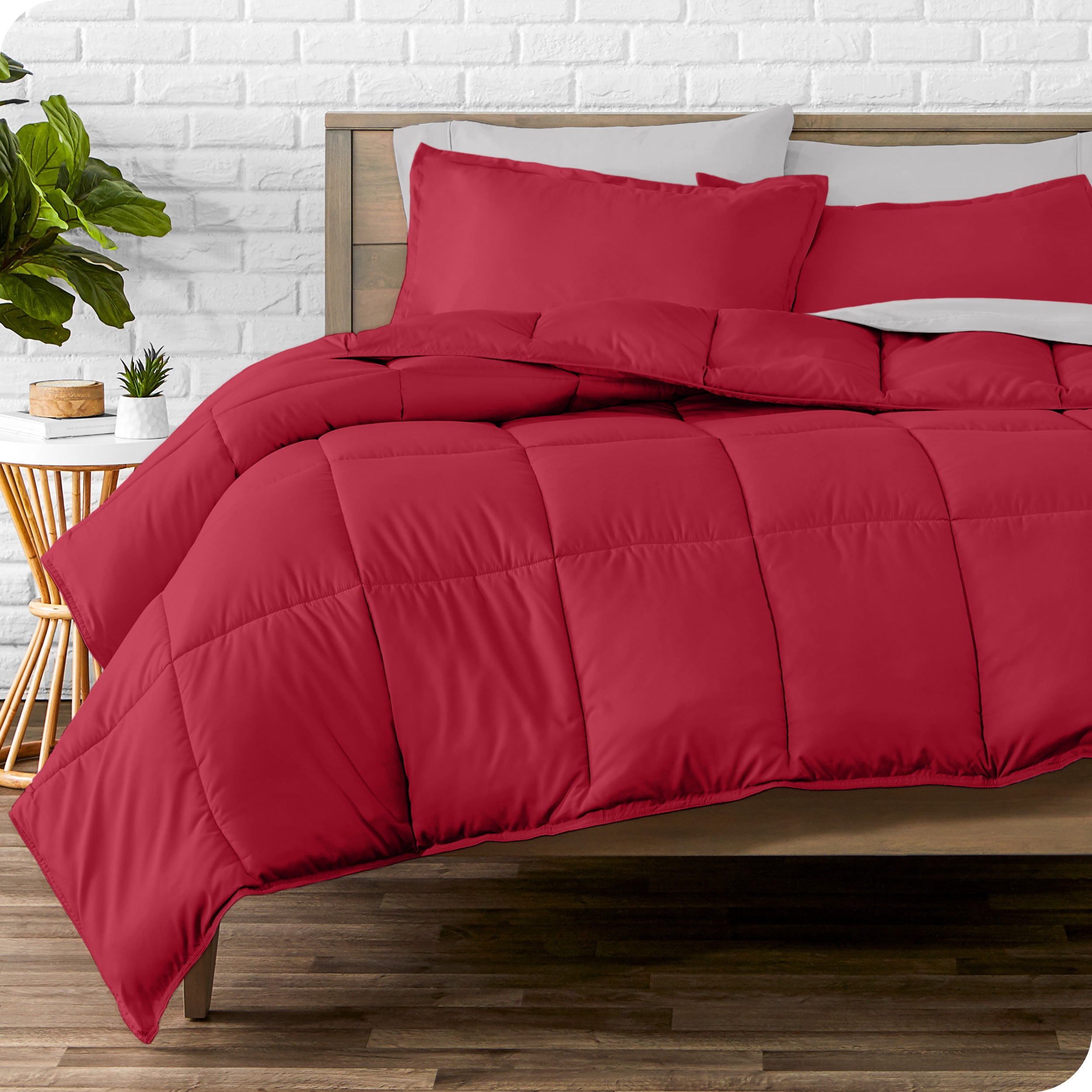A wooden bed frame with sheets, pillow shams and a comforter on the bed