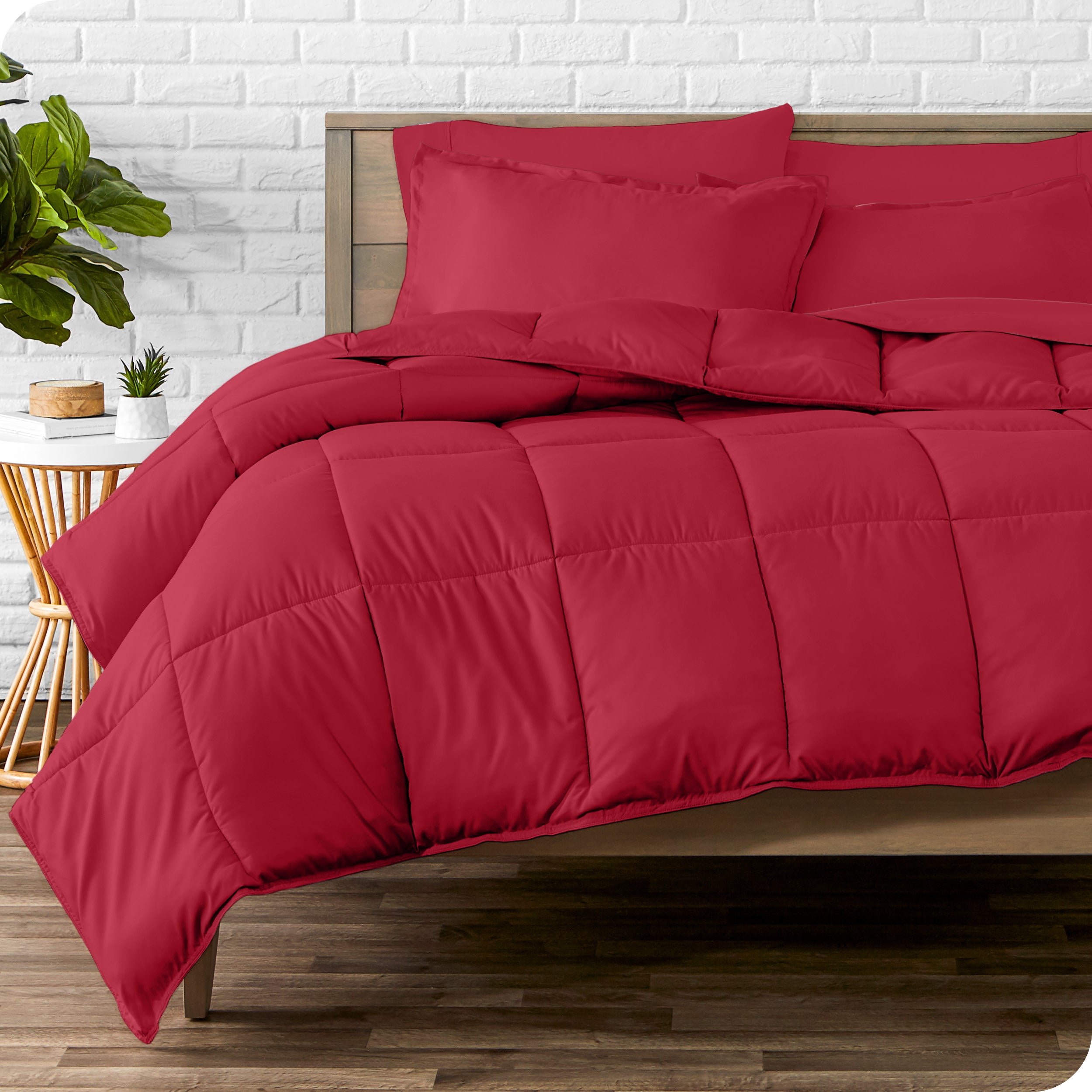 A wooden bed frame with sheets, pillow shams and a comforter on the bed