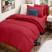 A college dorm room with a bed in a bag set on the mattress