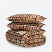 A folded stack of a printed flannel duvet cover with two pillows on top.