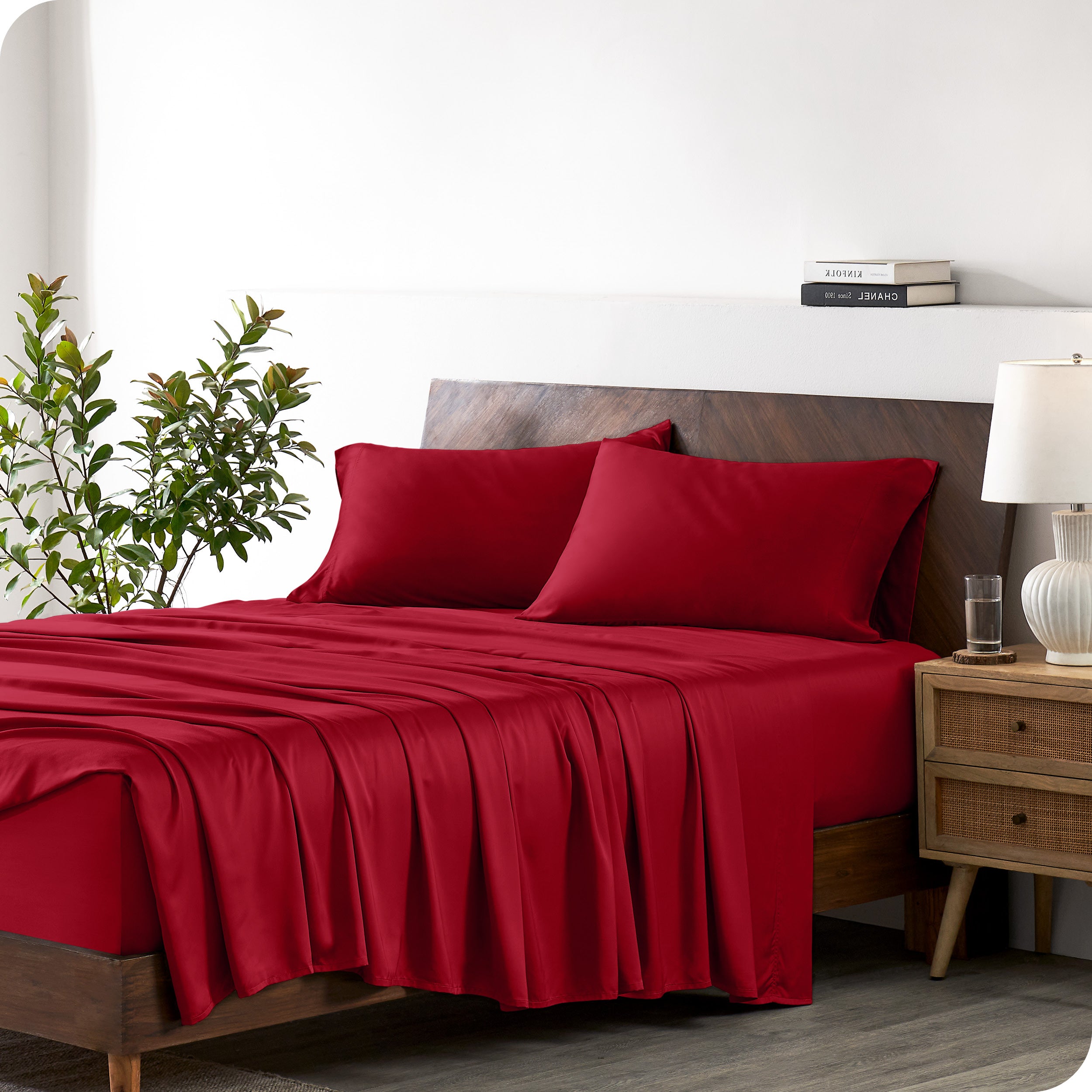Modern bedroom with a bed against a white wall with a nightstand next to the bed. The bed has bamboo sheets draped over it.