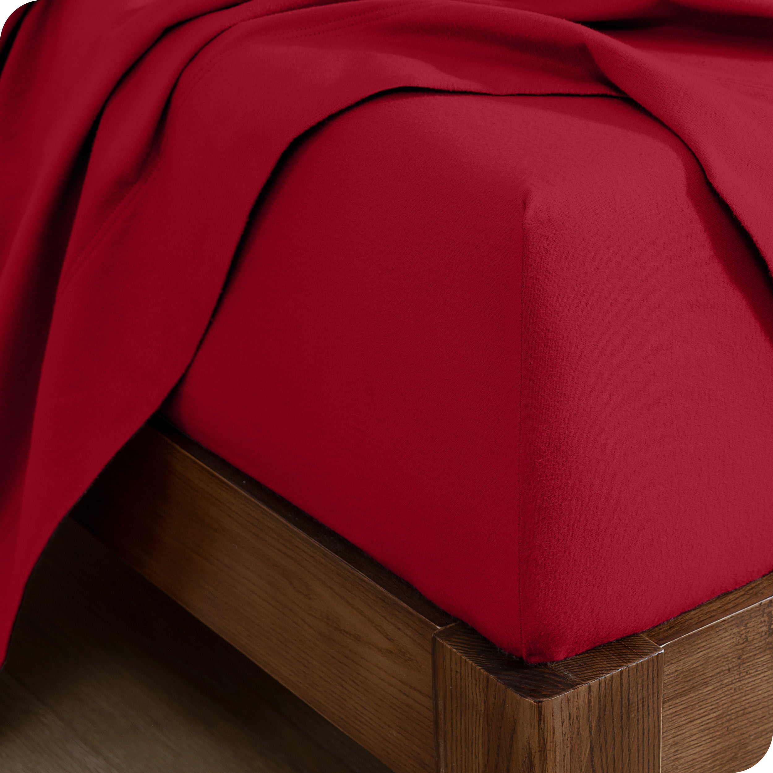 Close up of the corner of a mattress with a fitted sheet and flat sheet on it