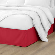 The corner of a bed with a bed skirt and comforter on it