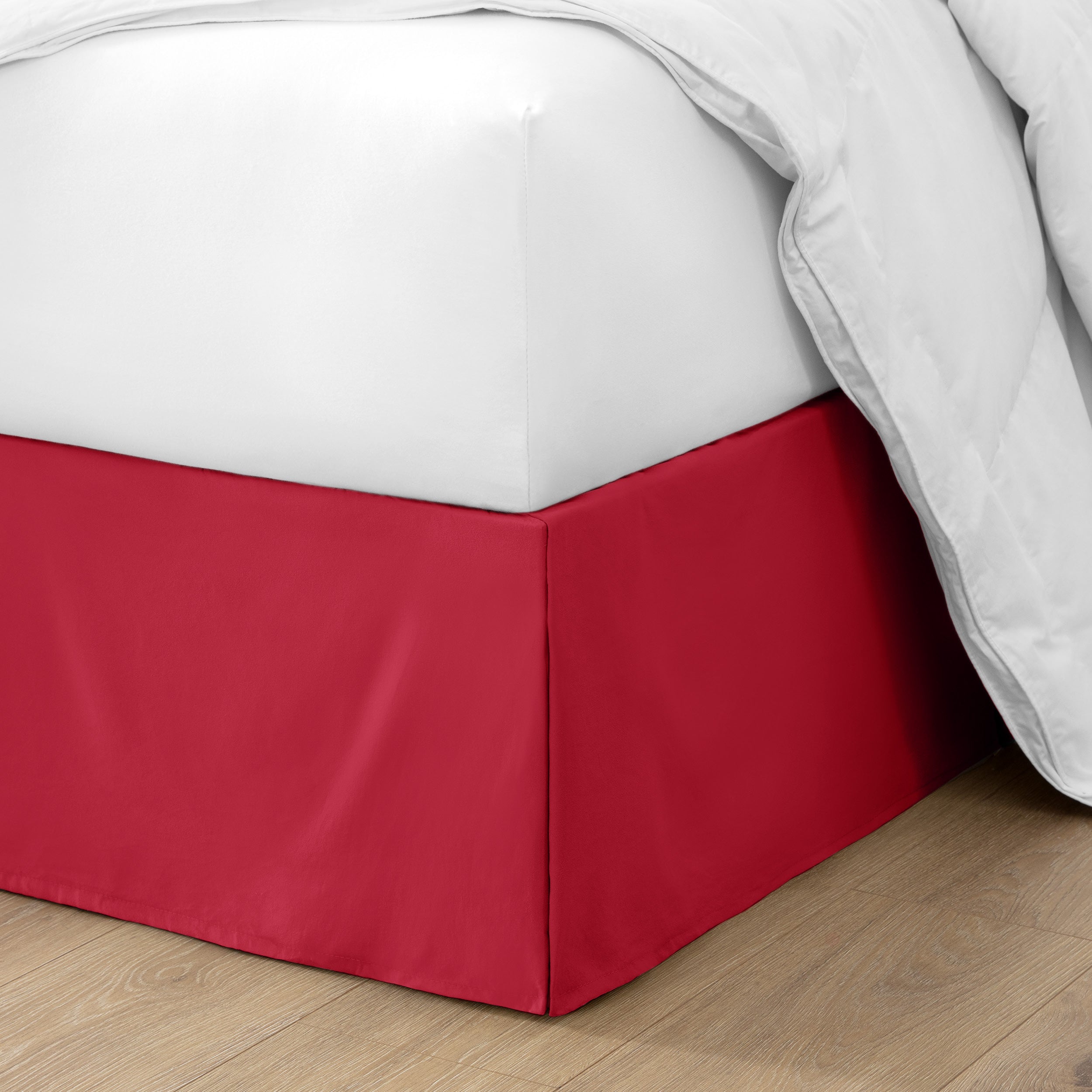 The corner of a bed with a bed skirt and comforter on it