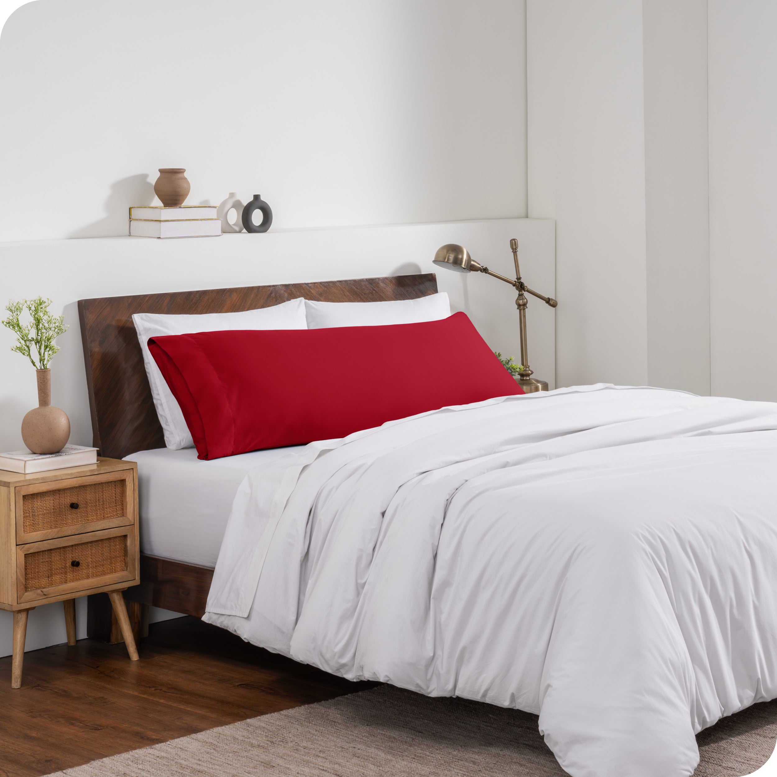 A body pillow cover on a pillow on a bed made with all white bedding