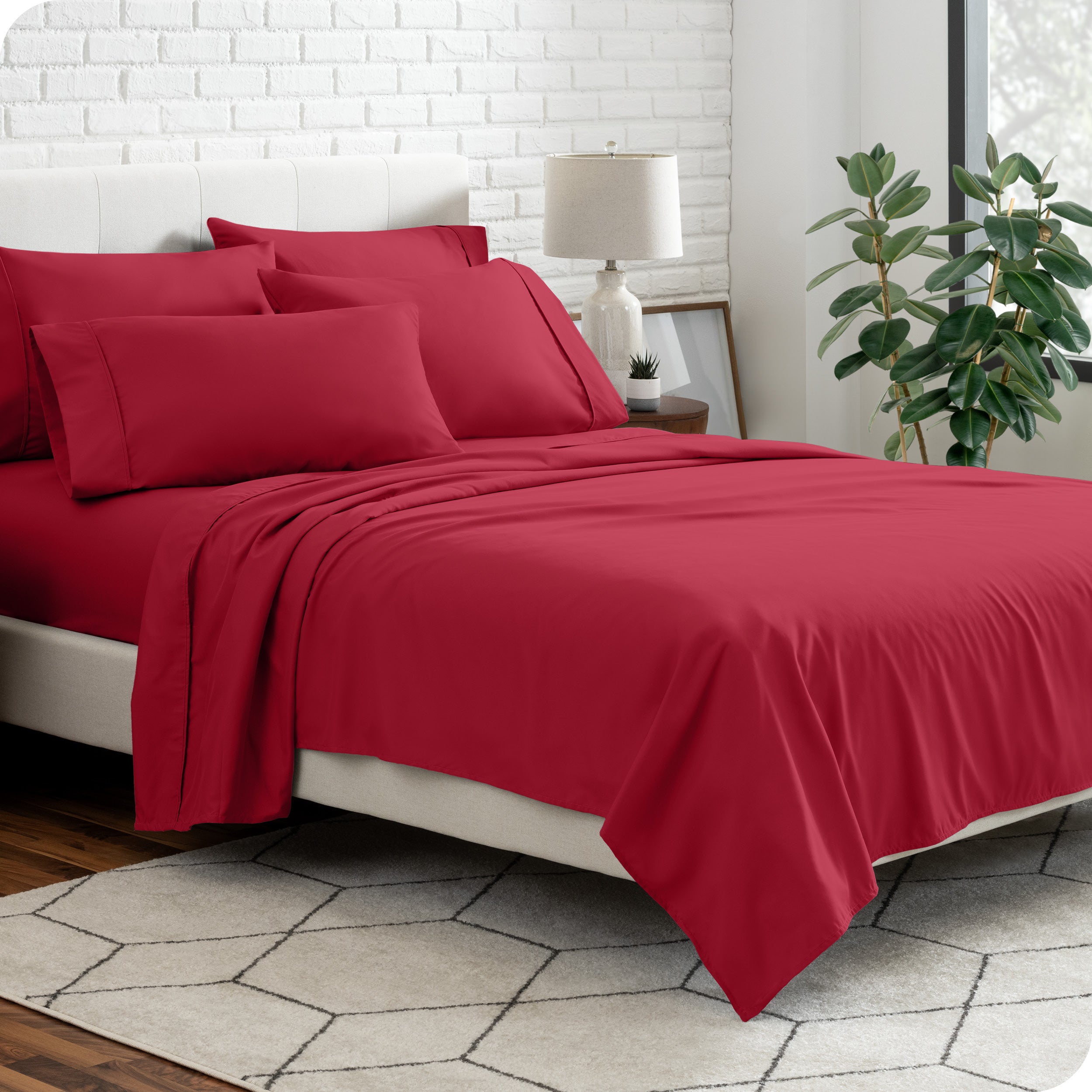 A bedroom setting with a bed made with the microfiber bed sheets and four pillows.