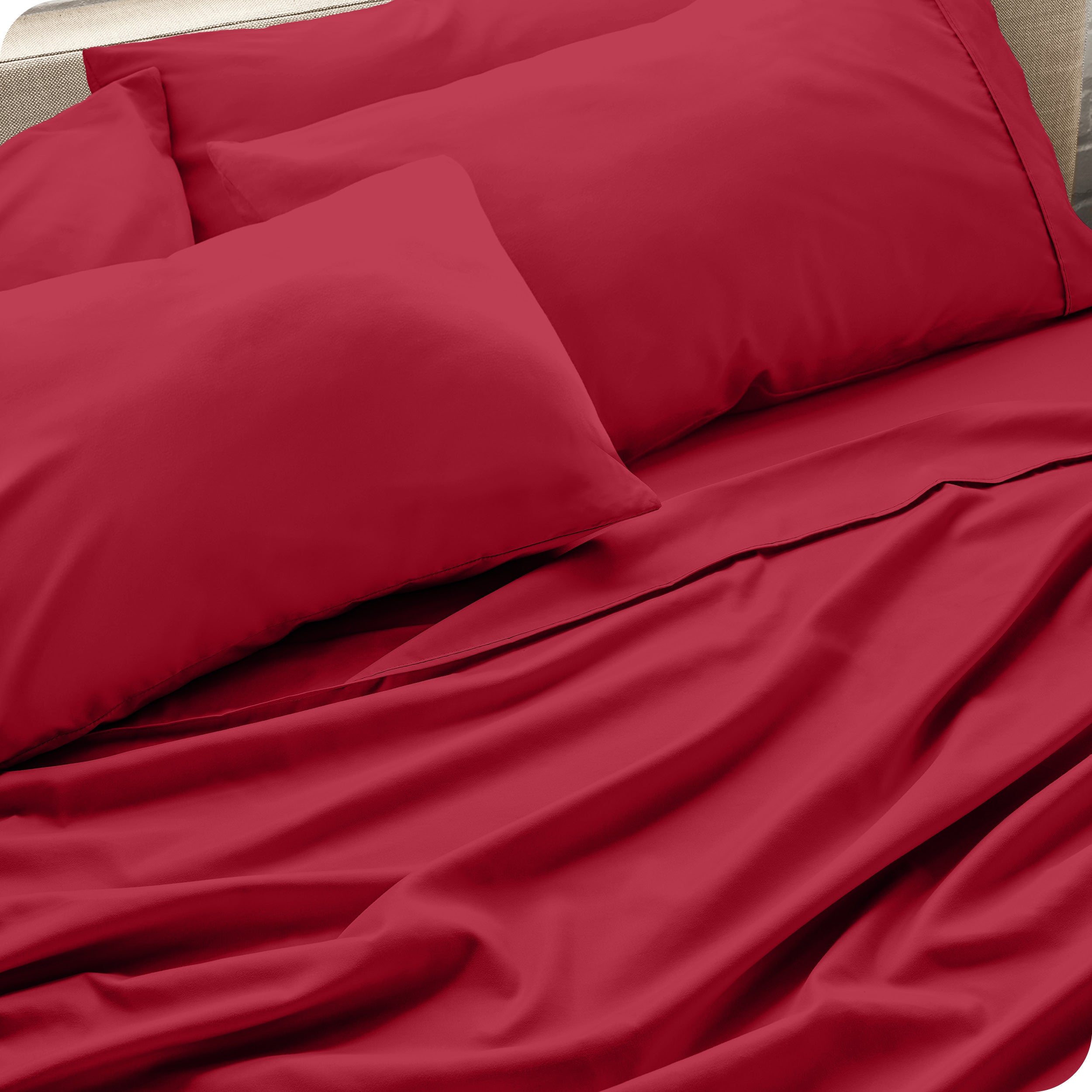 Close up of the microfiber bed sheets on a bed with four pillows.