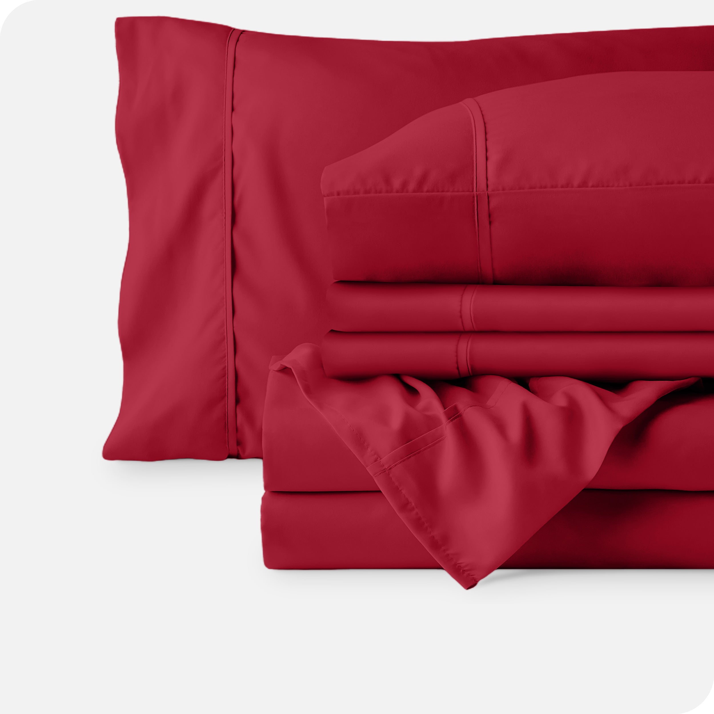Microfiber sheets neatly folded with corner draped over, two folded pillowcases and two display pillows.