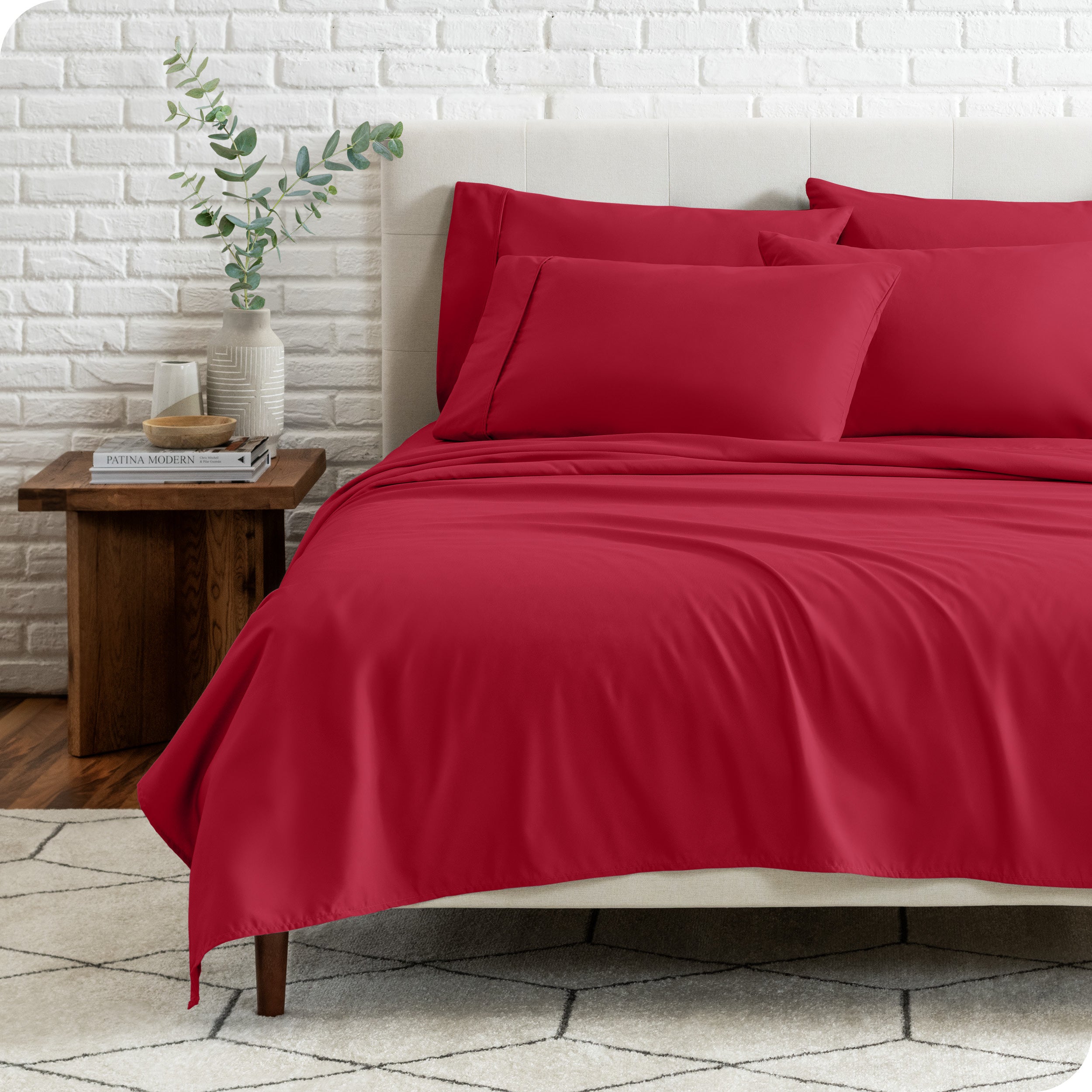 End view of a modern bed with the microfiber sheets on the bed with four pillows.