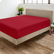 Corner view of a modern bed with a microfiber fitted sheet on the mattress. 