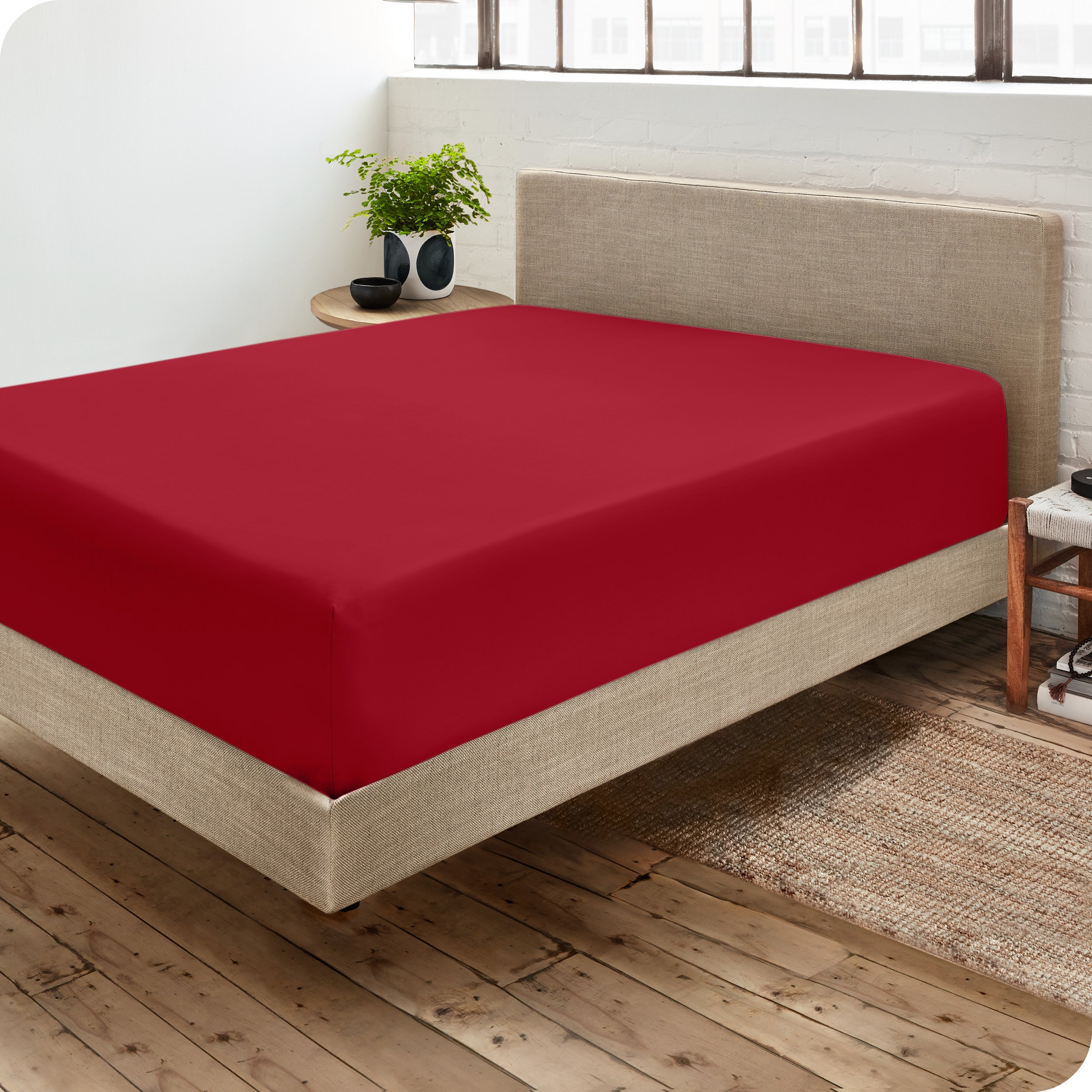 Corner view of a modern bed with a microfiber fitted sheet on the mattress. 